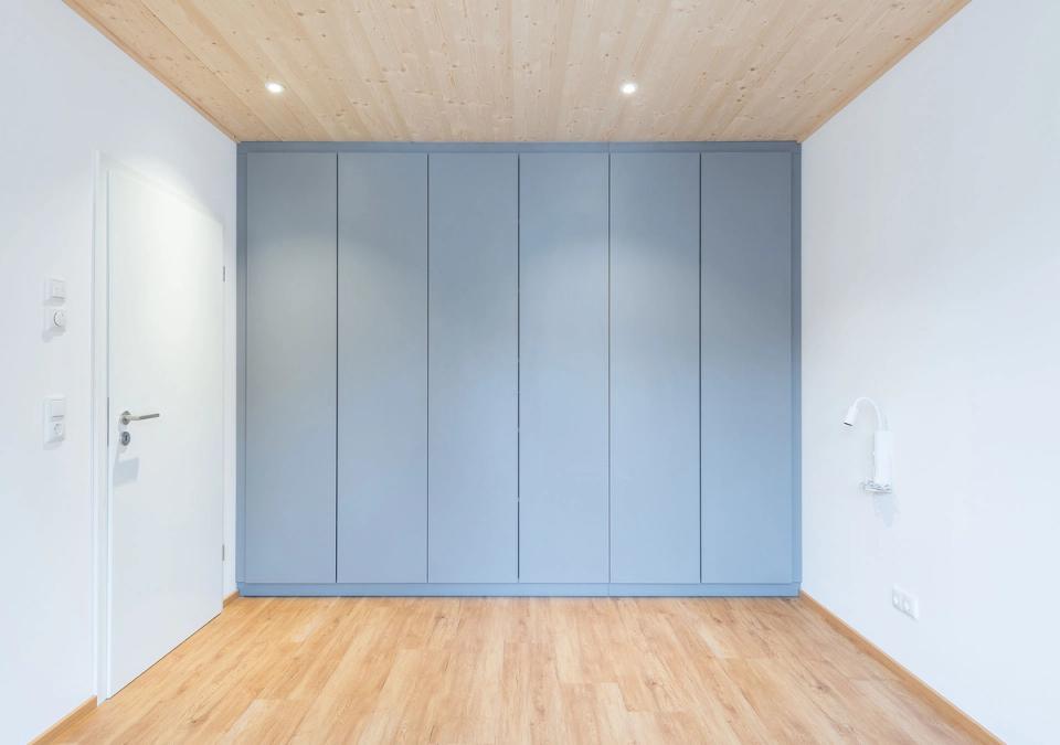Schlafzimmer mit blaugrauem Einbauschrank und Holzdecke