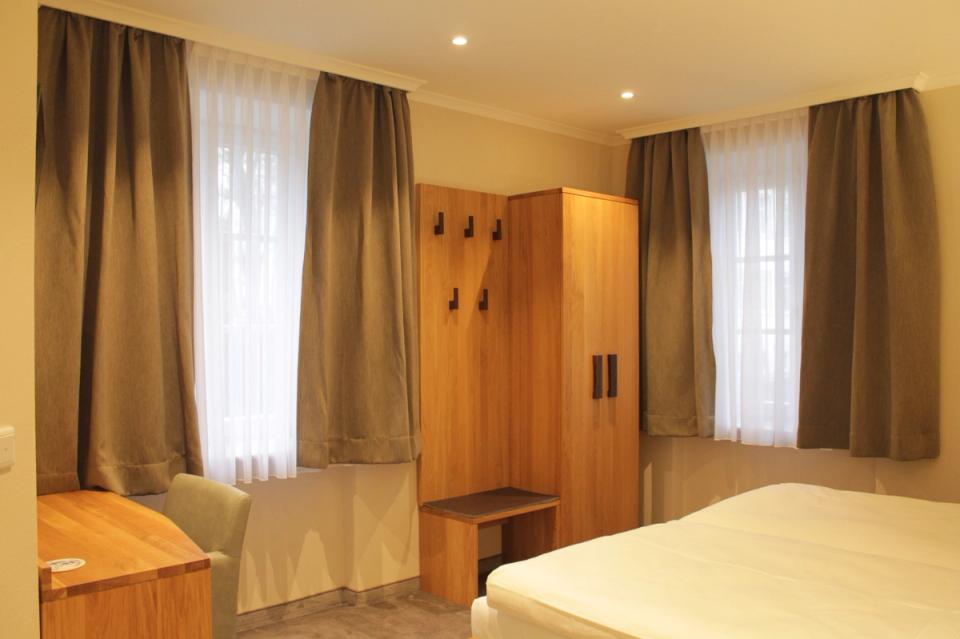Hotel Feuchtwangen — Hotelzimmer mit Holz-Kopfteil, Wandleuchten, gemütliche Atmosphäre