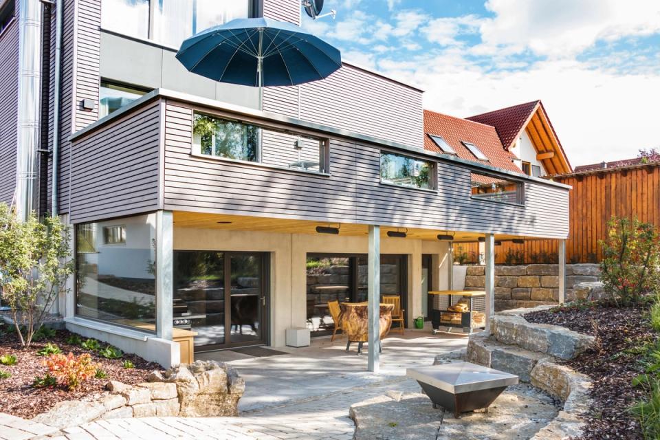 Terrasse mit Feuerschale unter dem auskragenden Obergeschoss mit Holzfassade