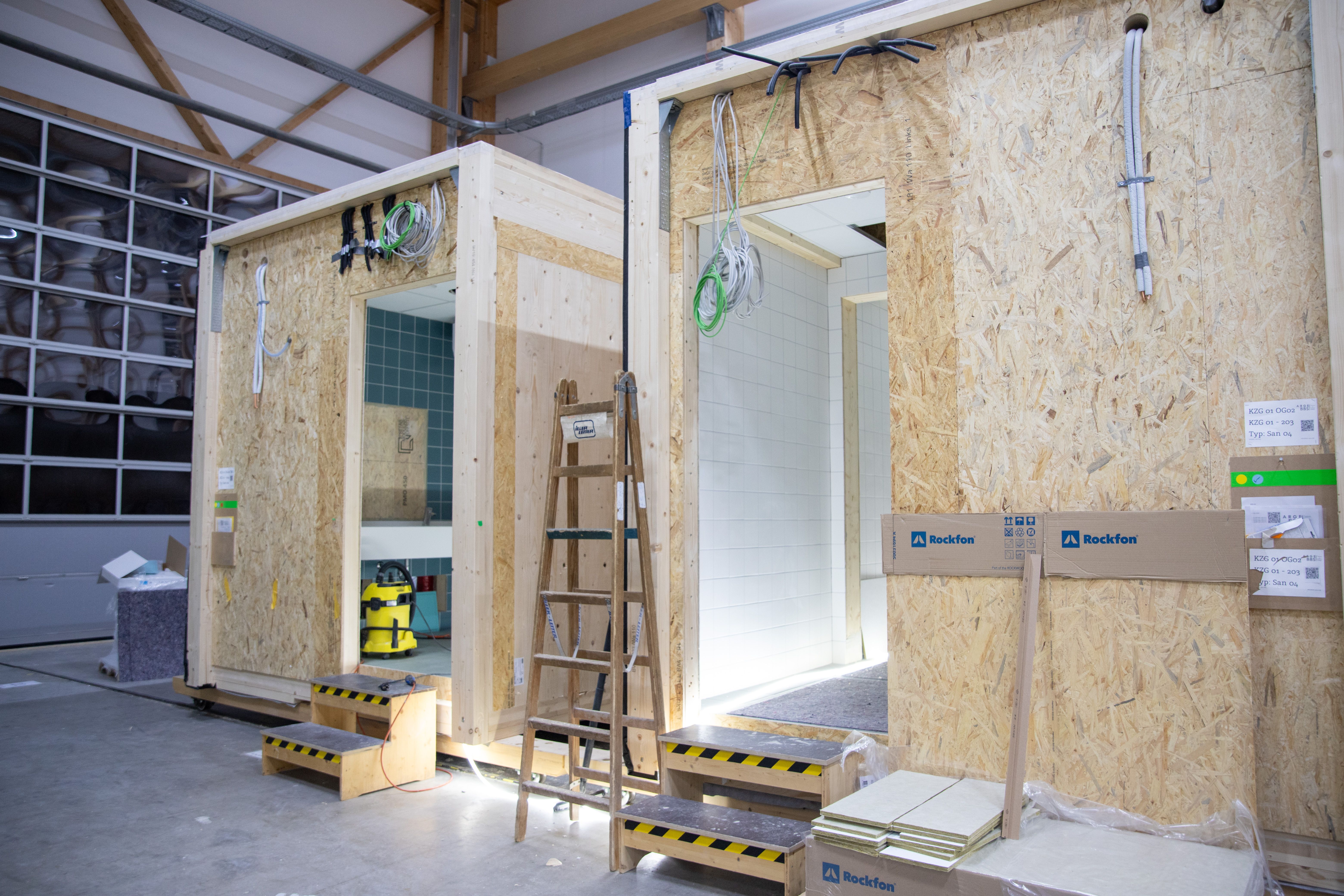 Sanitärmodule mit Stehleiter und Materiallager in der Produktionshalle der Zimmerei Stark