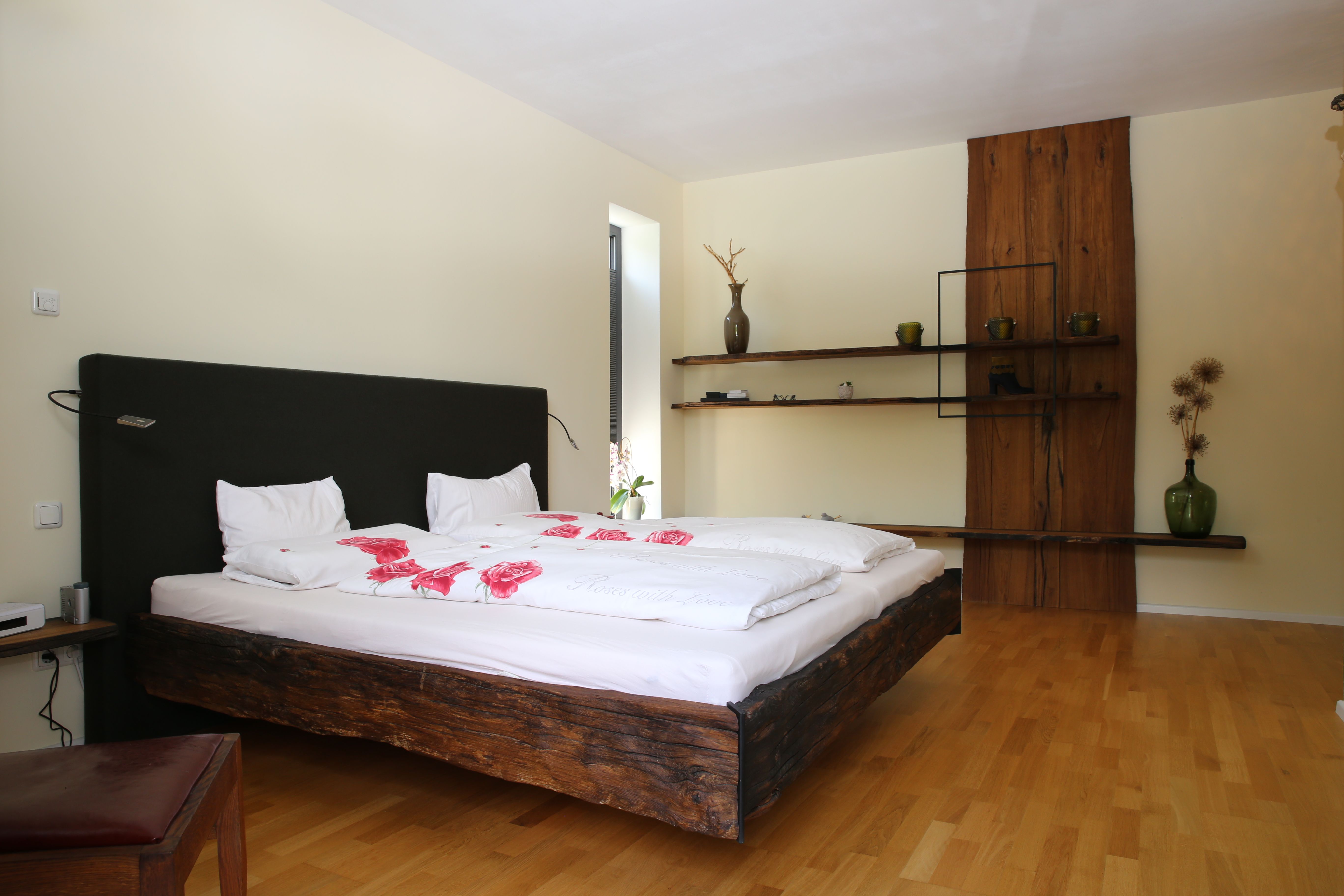 Schlafzimmer mit Altholz-Bettgestell und rustikalem Wandregal