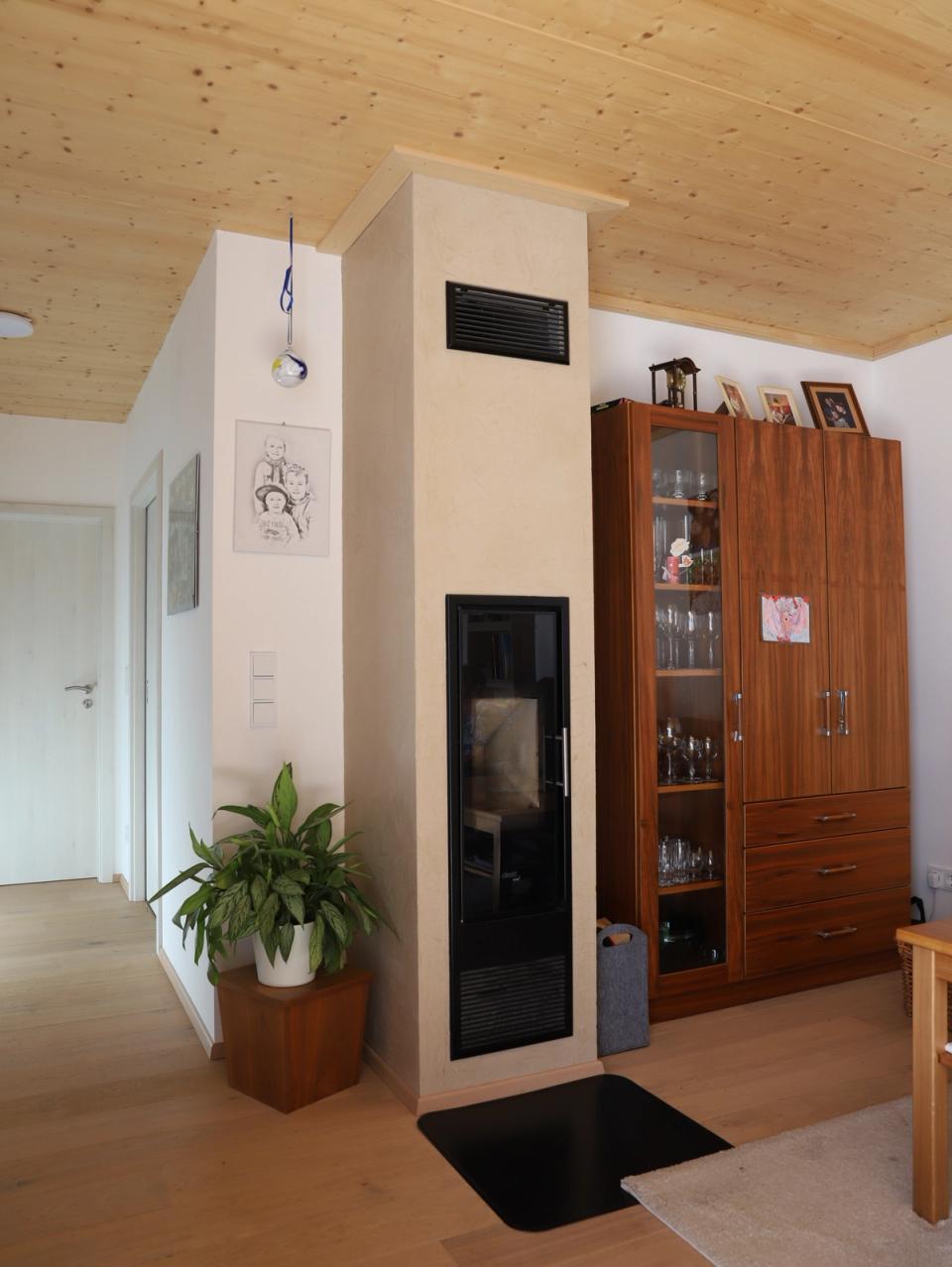 Wohnbereich mit Kaminofen, Vitrine und Holzwandverkleidung