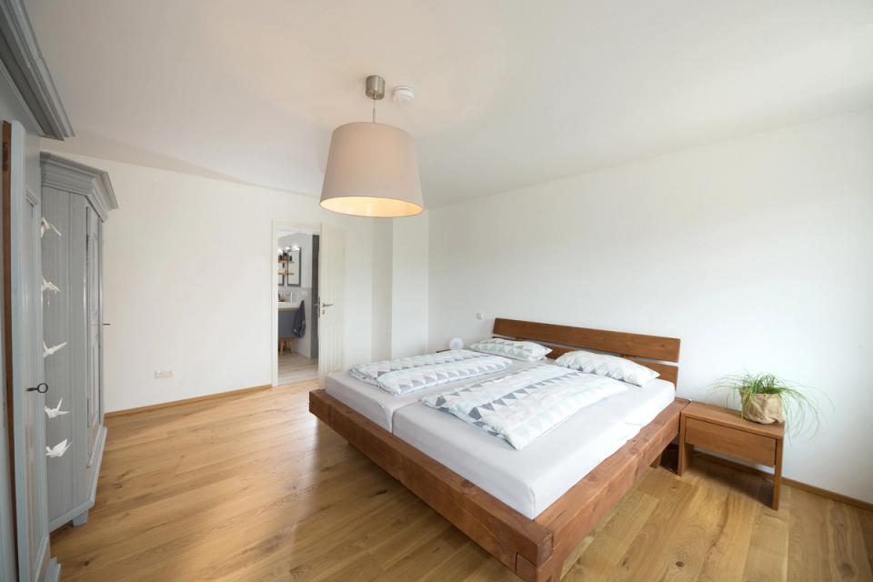 Schlafzimmer mit Massivholzbett und Durchgang zum Bad