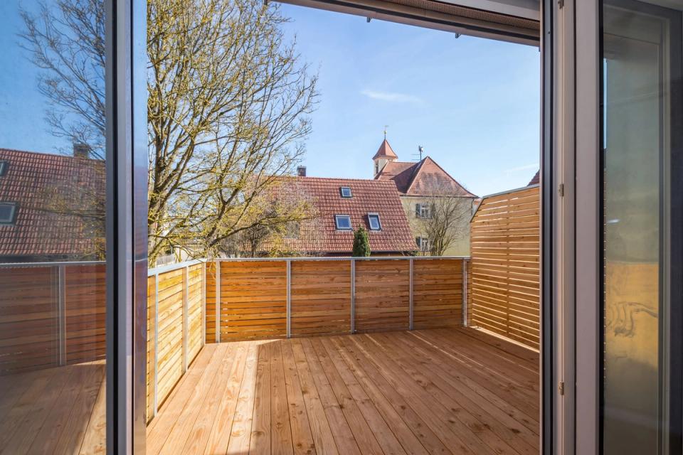 Holzterrasse mit Sichtschutz und Blick über Dächer zur Kirchturmspitze