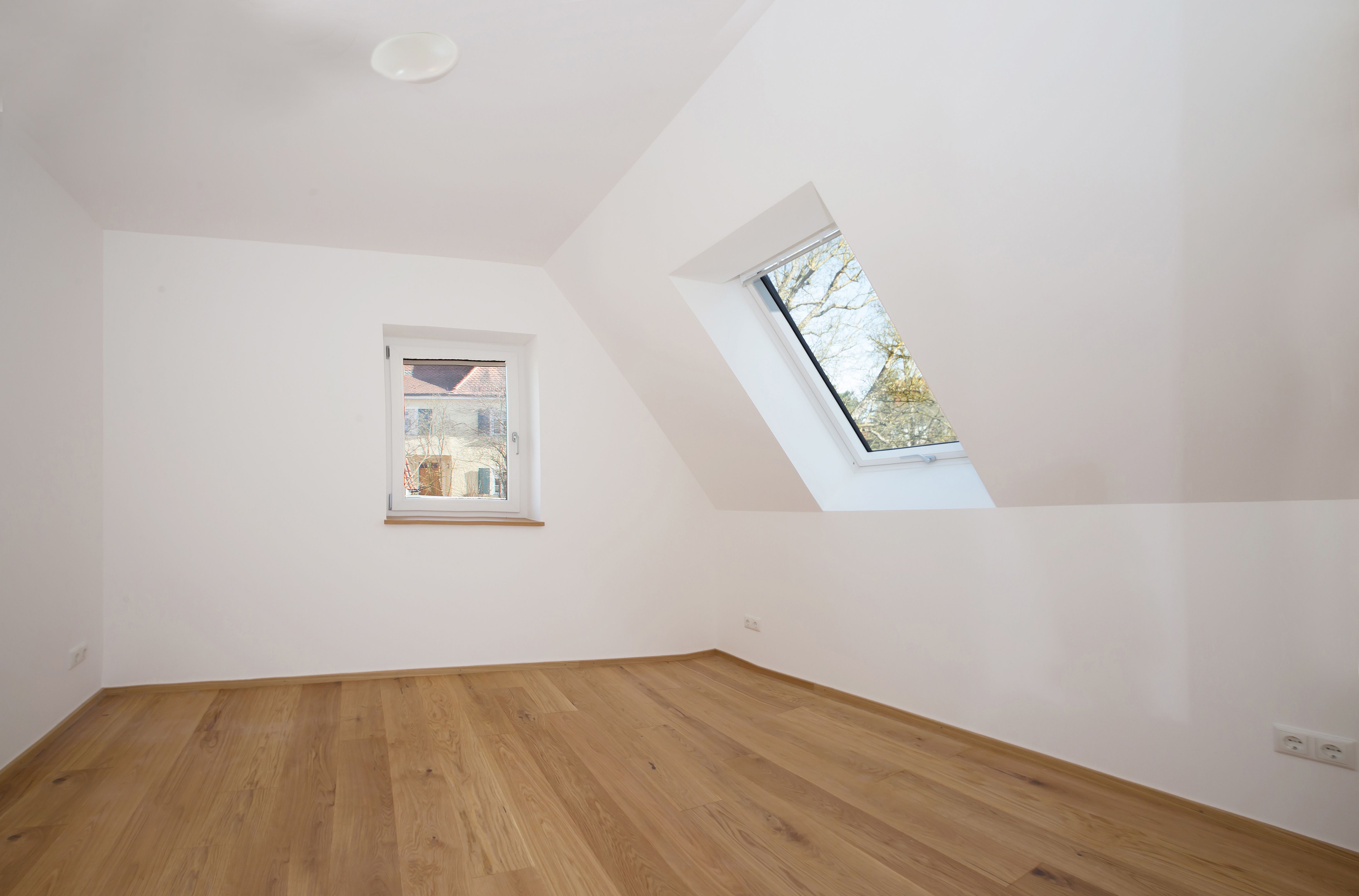 Ausgebautes Dachzimmer mit Gaubenfenster und Parkett