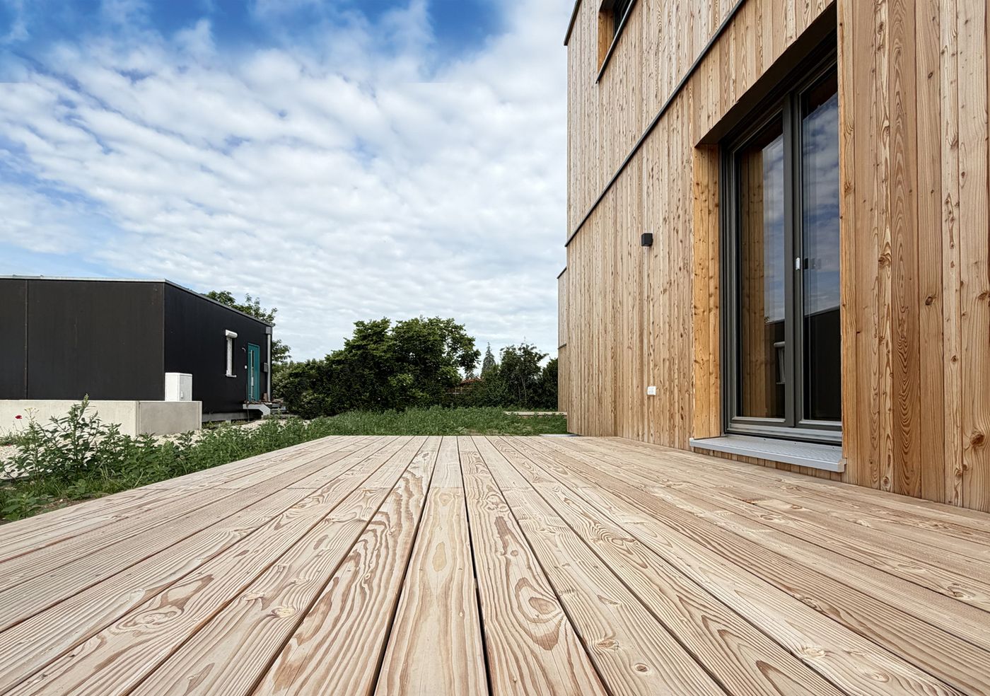 Die Holzterrasse liegt direkt vor dem Wohnbereich.