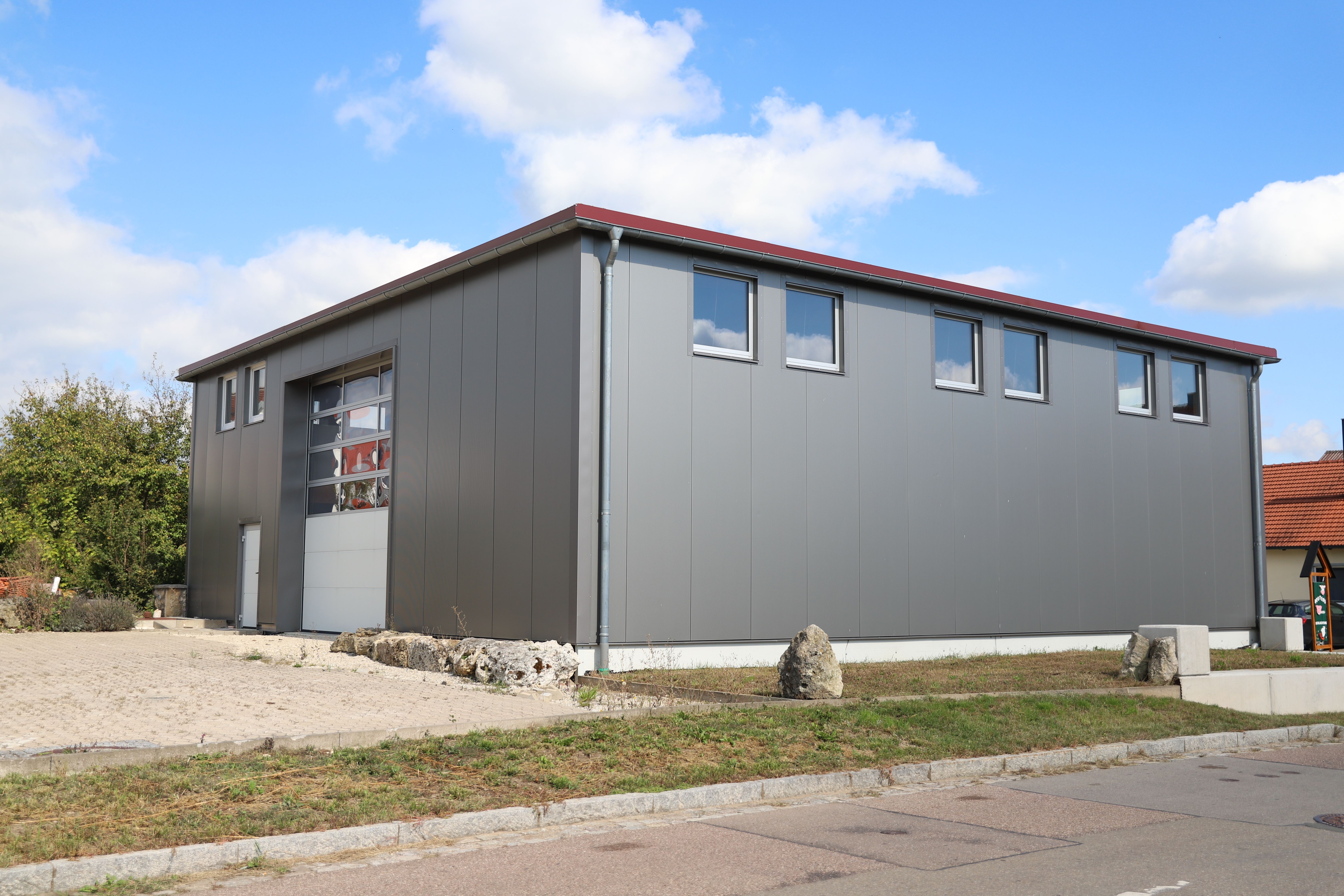Lagerhalle Steinhart — graue Gewerbehalle mit rotem Dach, Außenansicht