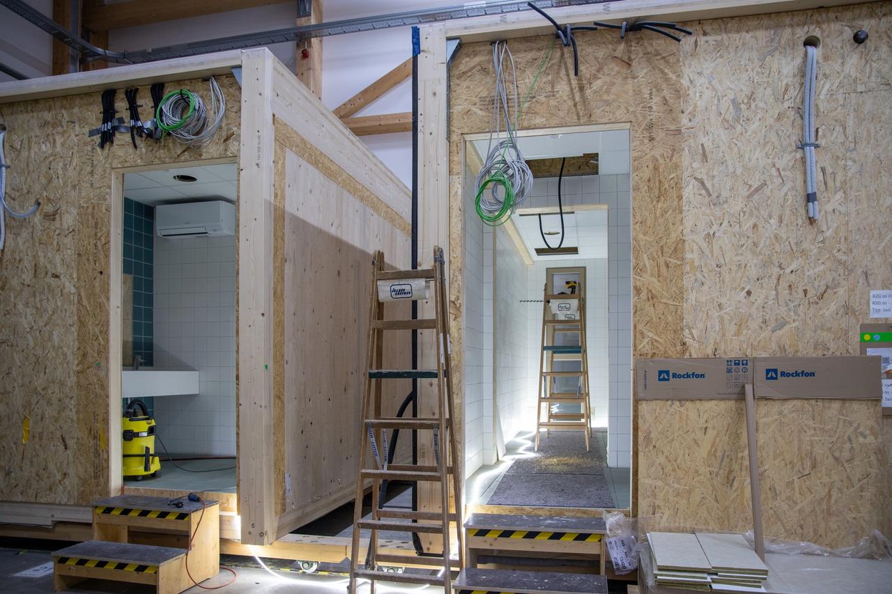 Zwei Sanitärmodule mit Leitern während der Endmontage in der Halle