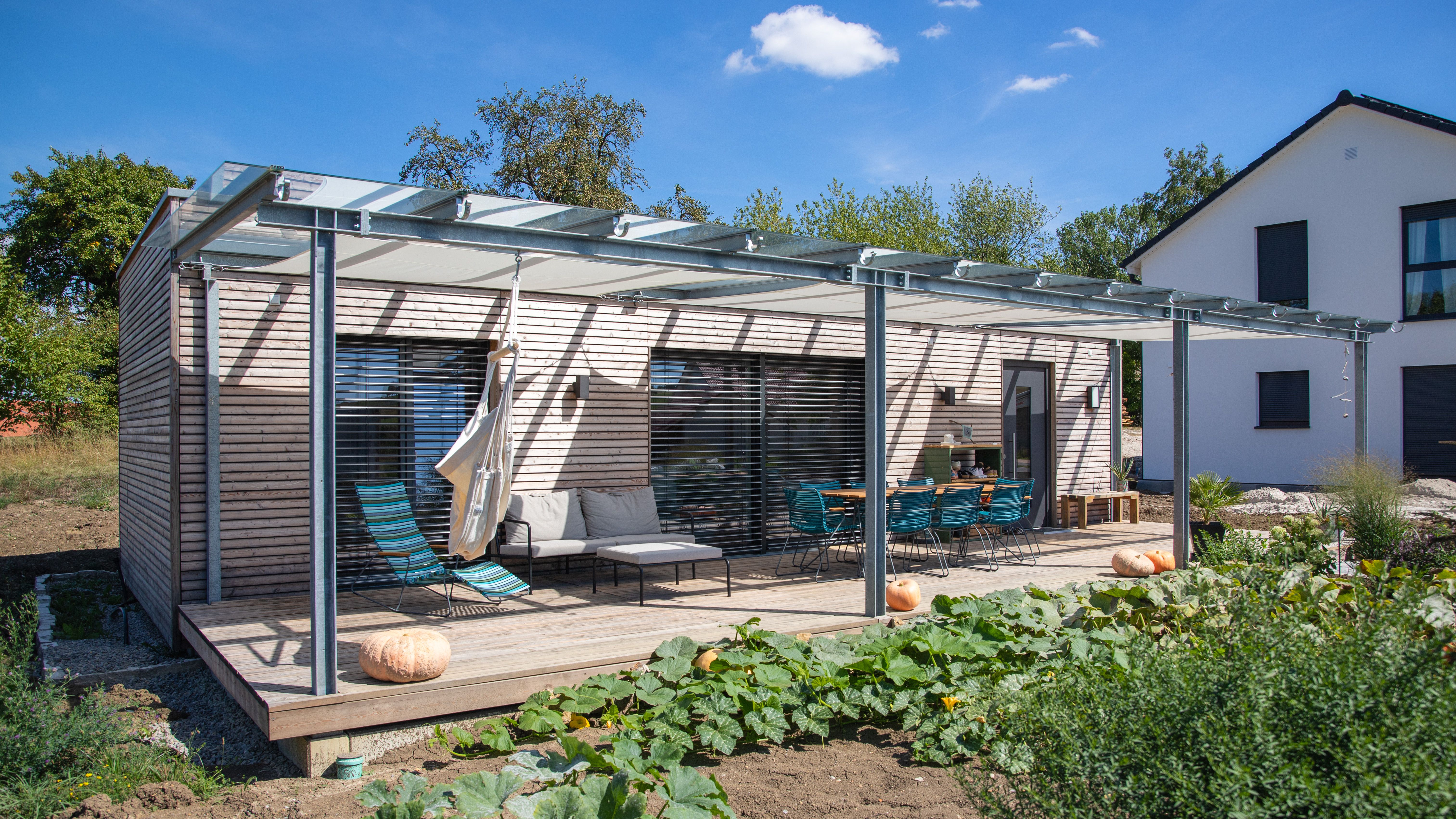 Eingeschossiges Modulhaus mit Terrasse, Pergola und Gemüsegarten