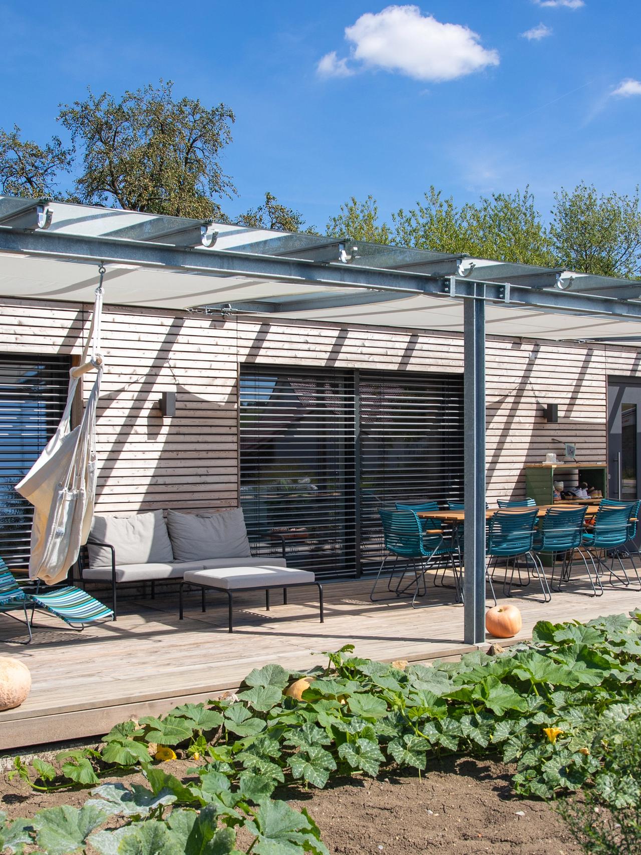 Eingeschossiges Modulhaus mit Terrasse, Pergola und Gemüsegarten