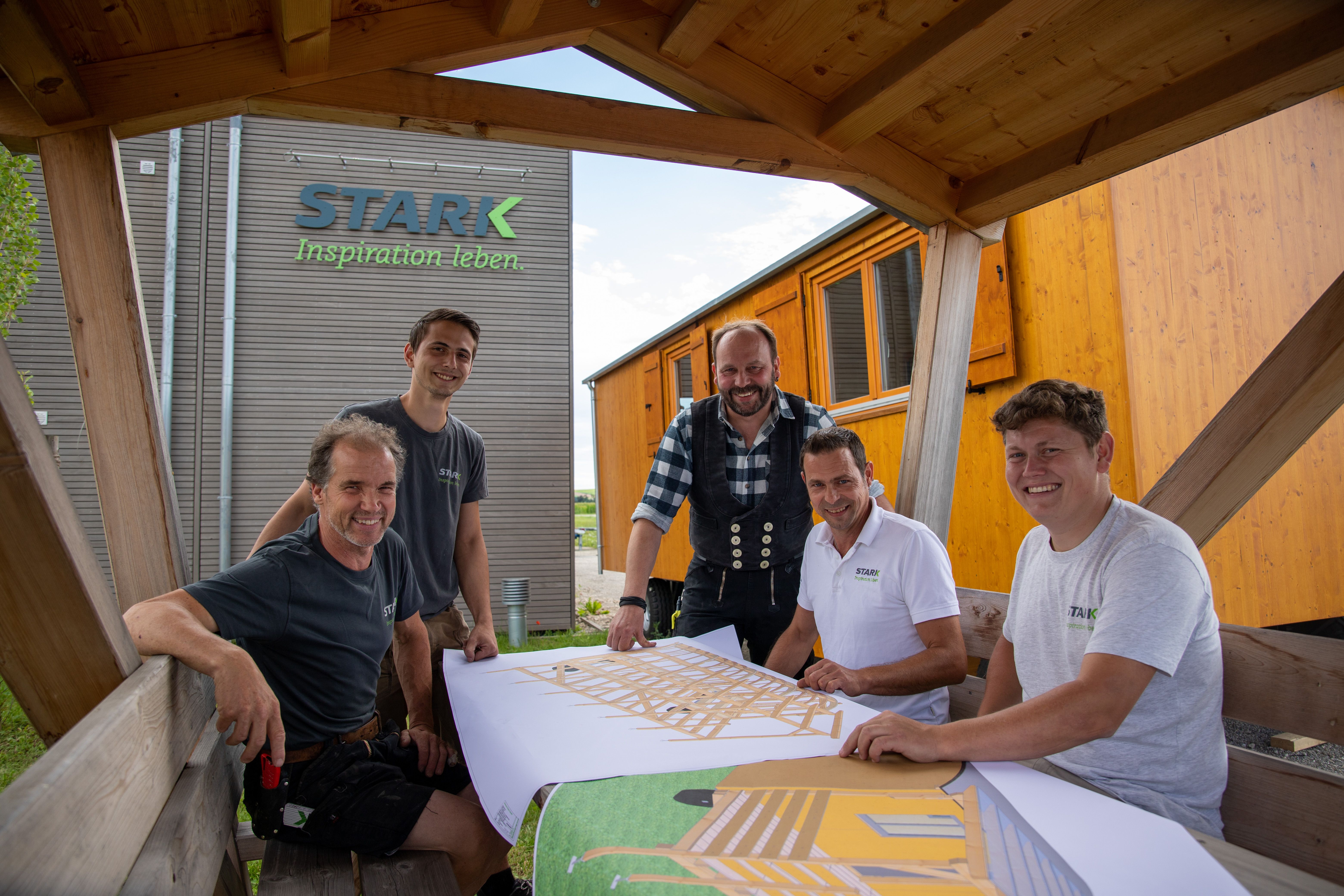 Das Team der Manufaktur am Plantisch, dahinter ein fertiger Waldkindergartenwagen