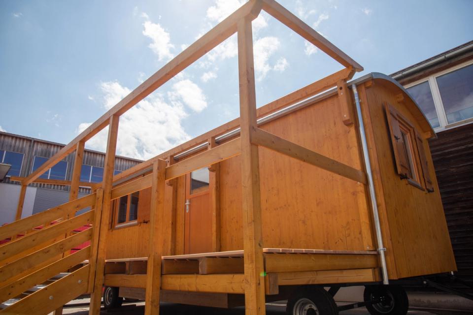 Honigfarbener Waldkindergartenwagen mit Terrasse und Gerüst für ein Sonnendach, von unten gesehen