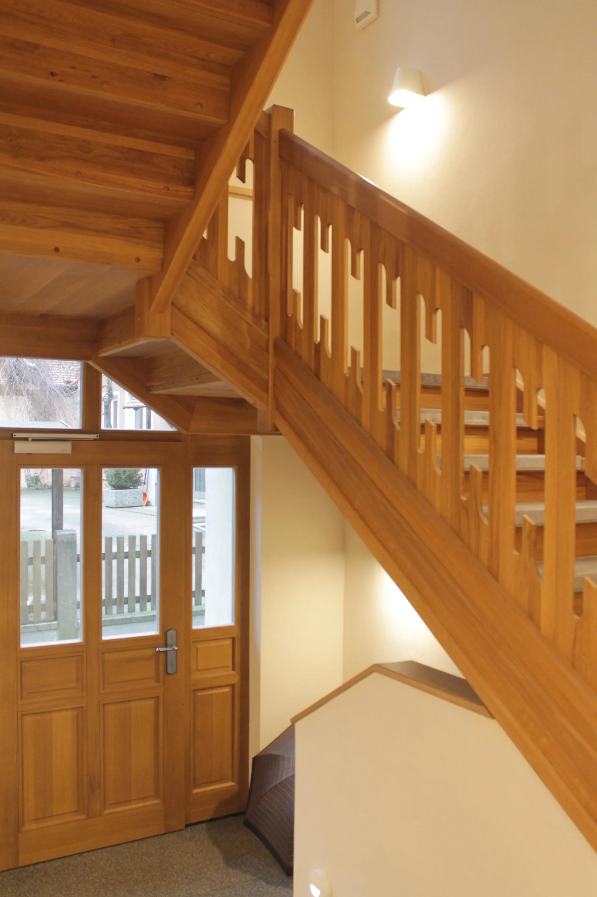 Holztreppe mit durchbrochenem Geländer und Blick zum Hoteleingang