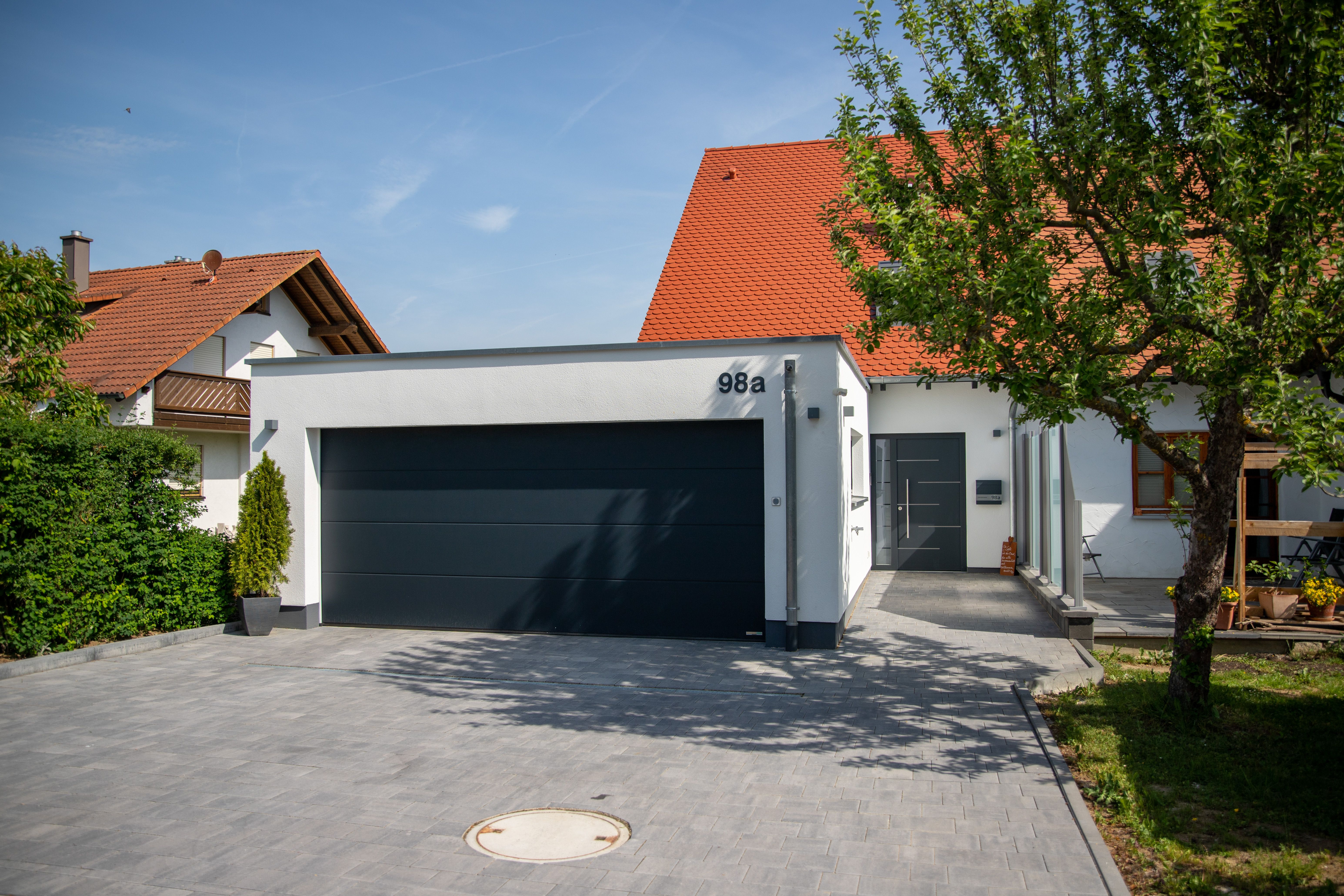 Garage mit Anbau und rotem Satteldach im Garten