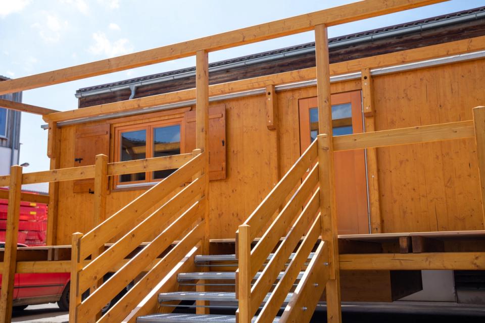 Treppen und Geländer an der Terrasse eines honigfarbenen Waldkindergartenwagens