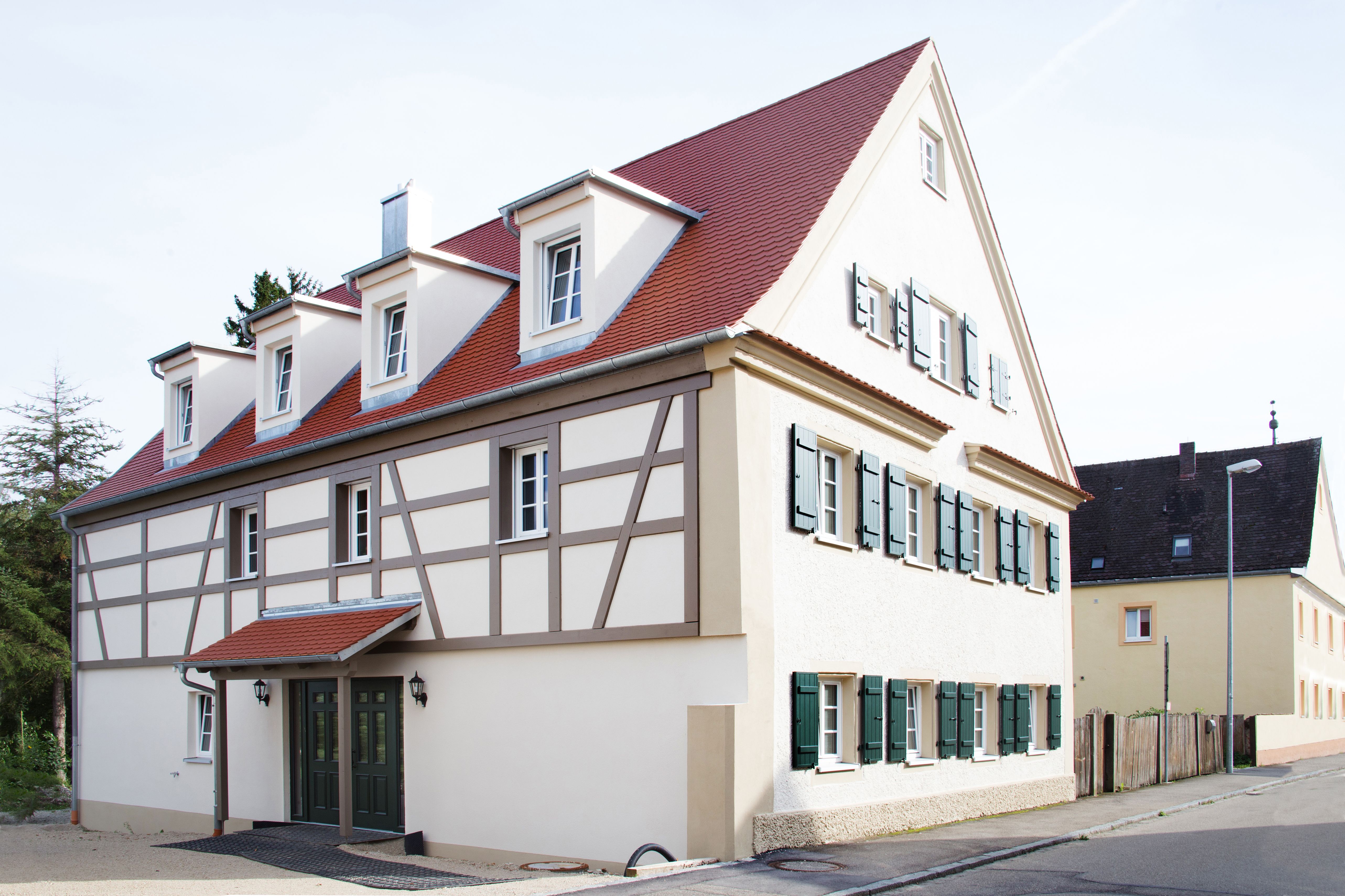 Saniertes Fachwerkhaus mit grünen Läden und Eingang über Eck