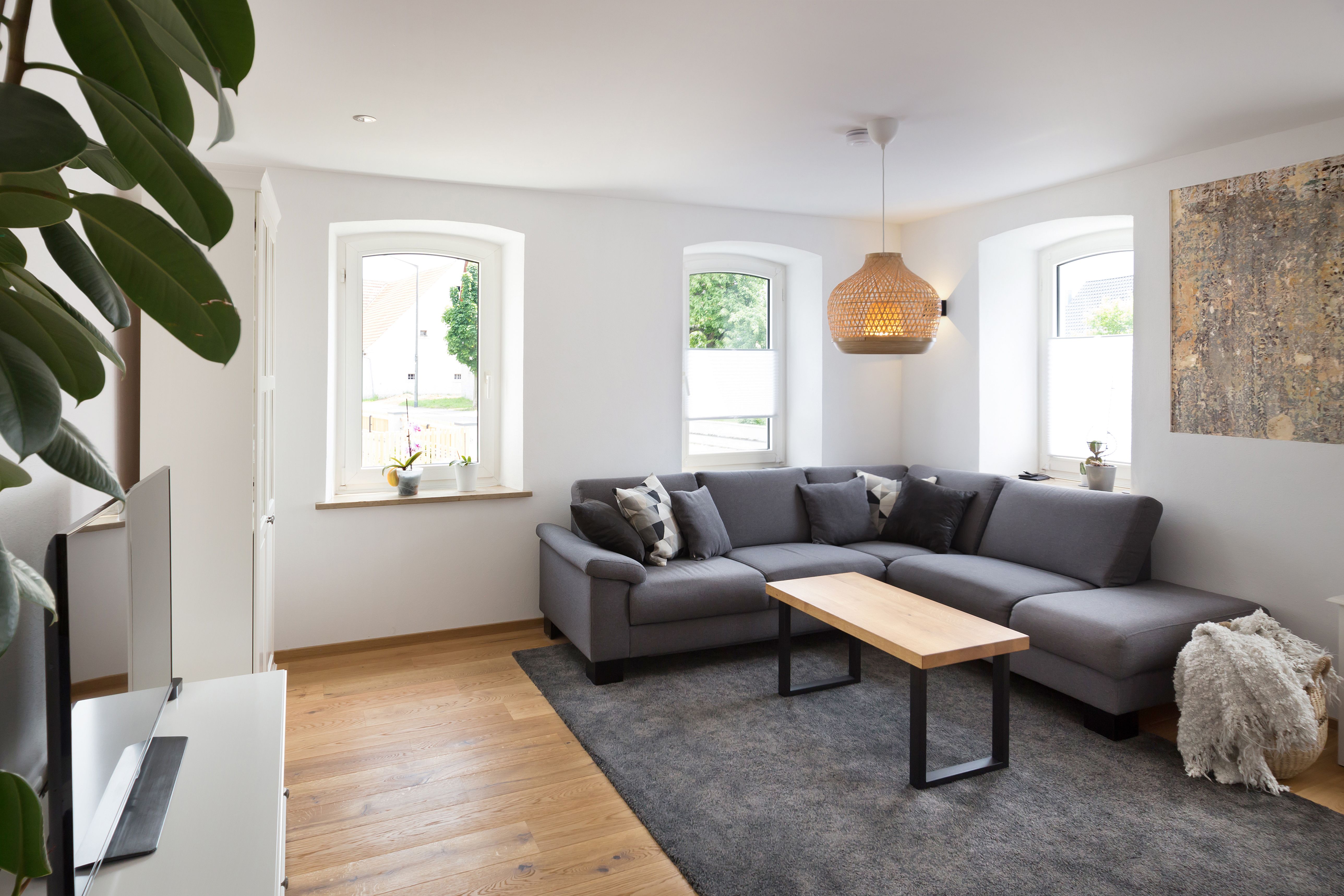 Helles Wohnzimmer mit grauem Sofa und Rundbogenfenstern