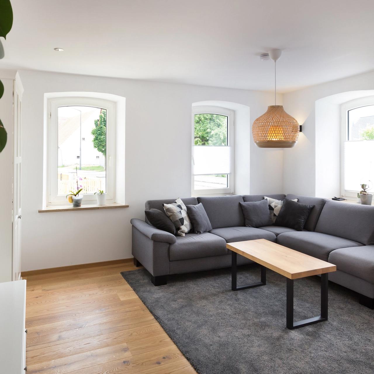 Helles Wohnzimmer mit grauem Sofa und Rundbogenfenstern