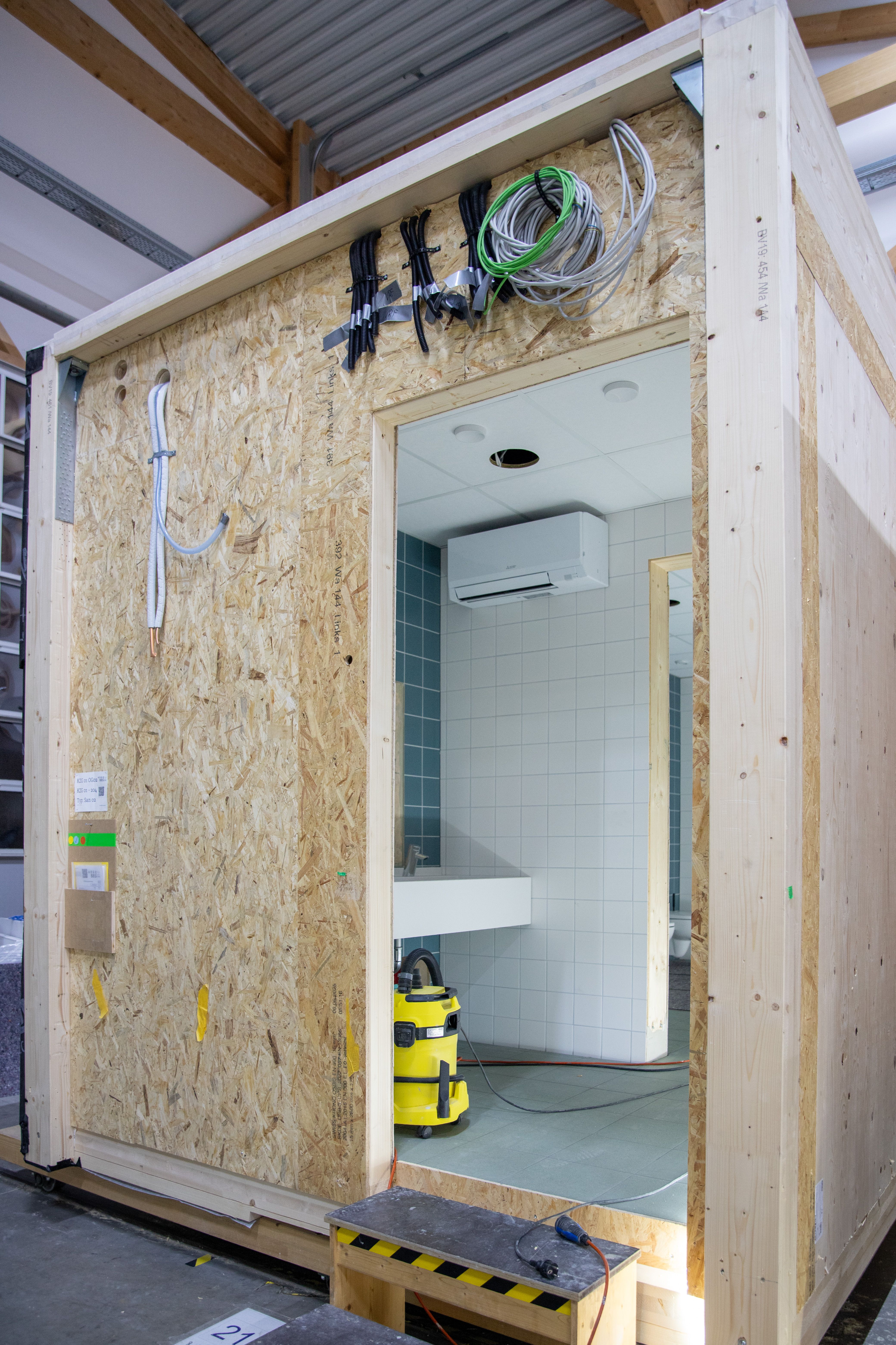 Blick durch die Türöffnung eines Sanitärmoduls auf das geflieste Bad