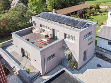 Luftaufnahme des Musterhauses mit Dachterrasse und Photovoltaikanlage