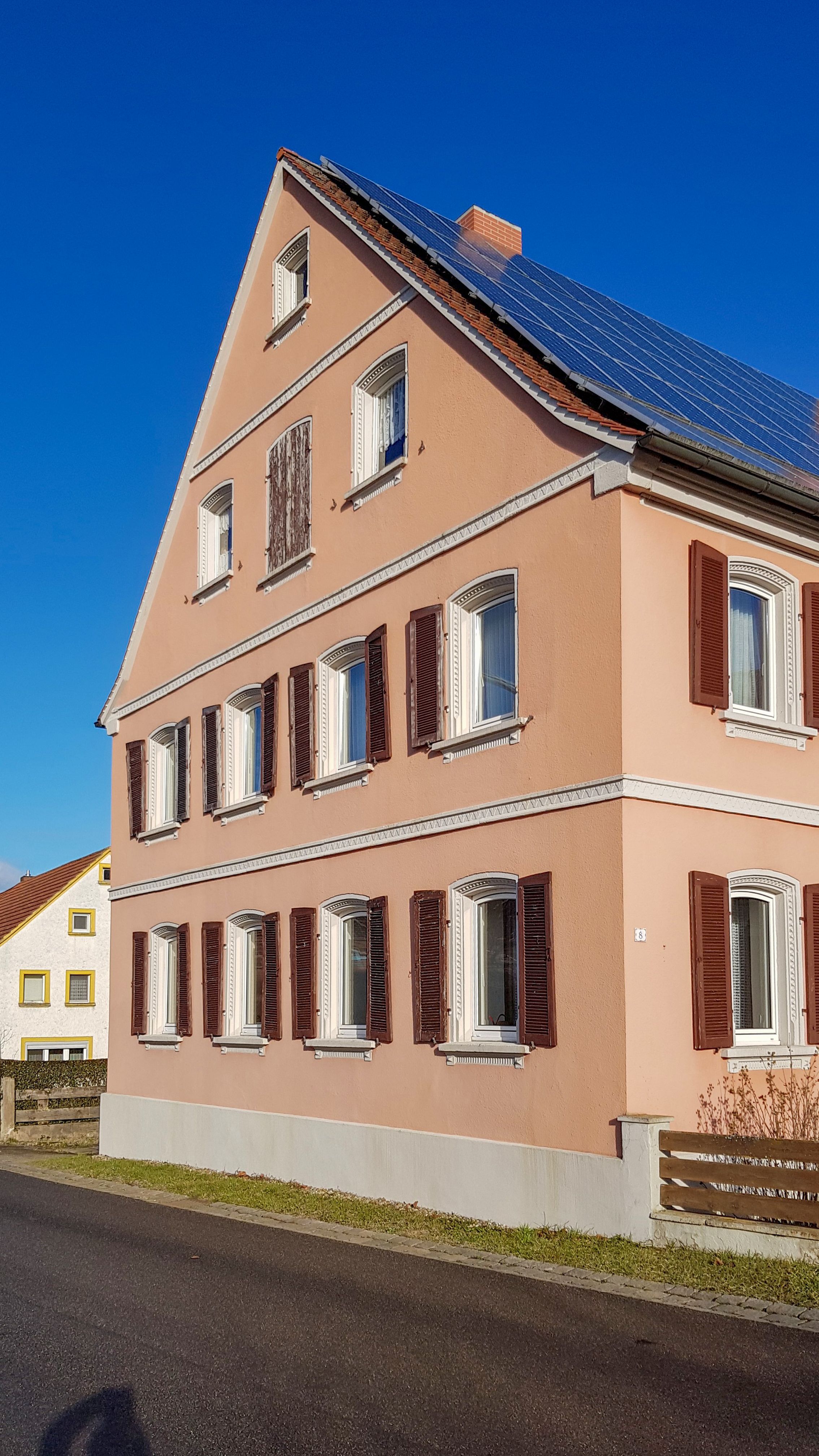 Unsanierte Fassade in Altrosa mit braunen Klappläden