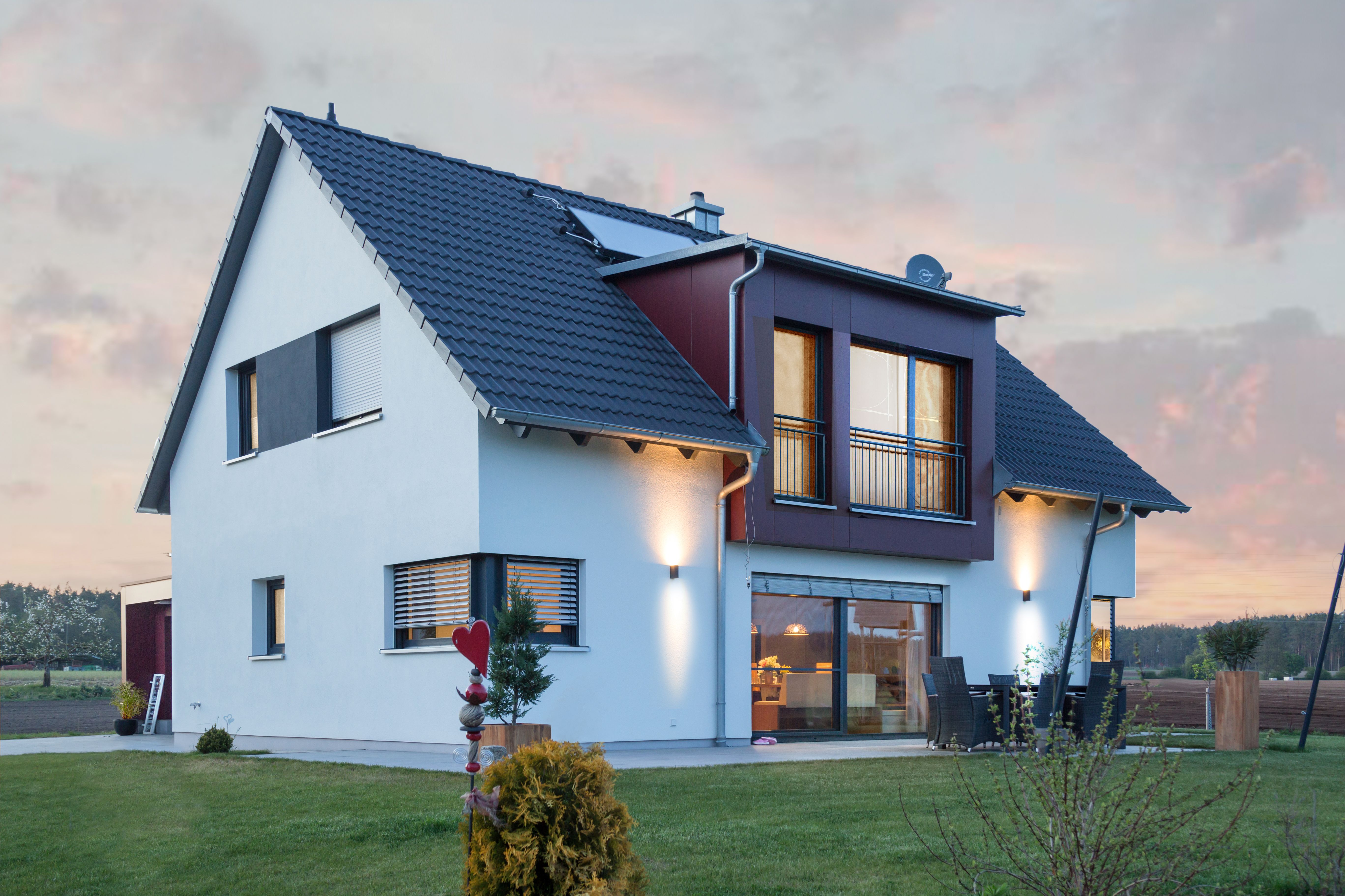 Beleuchtete Hausfassade mit Wandleuchten in der Abenddämmerung