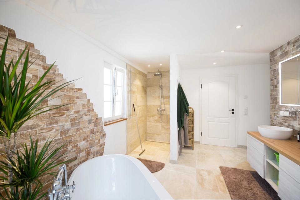 Modernes Bad mit Natursteinwand, freistehender Wanne und ebenerdiger Dusche