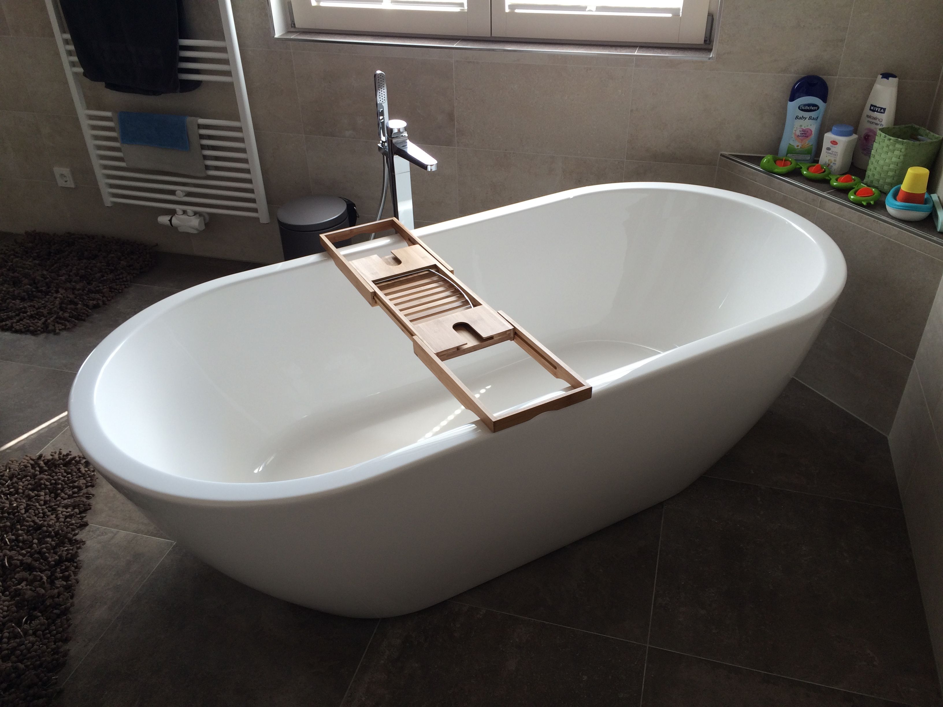 Freistehende Badewanne mit Holzablage am Fenster