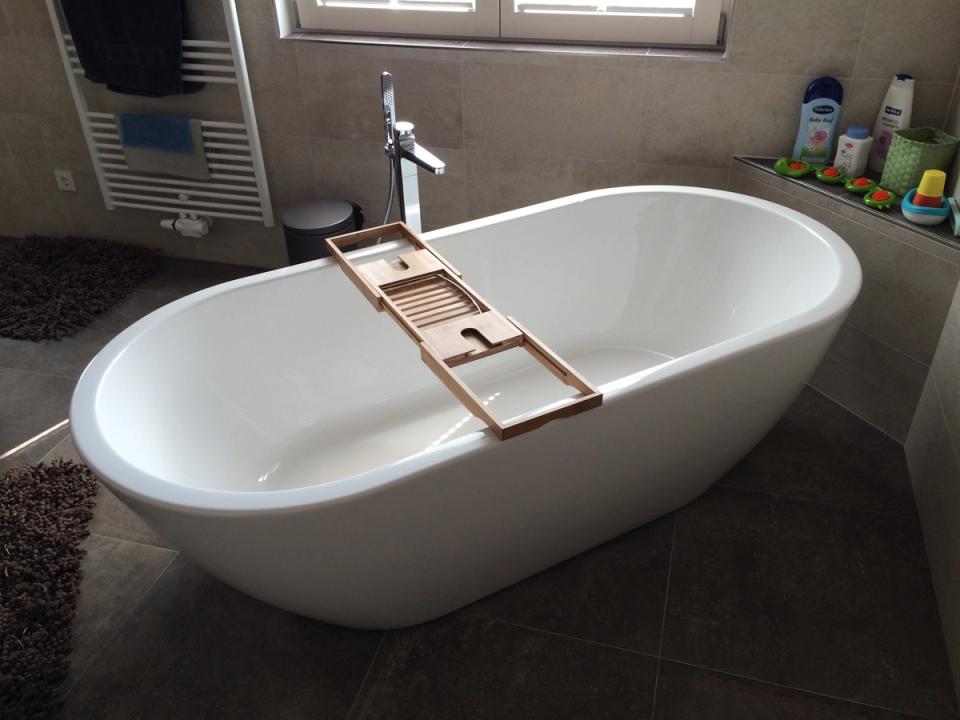 Freistehende Badewanne mit Holzablage am Fenster im Badezimmer