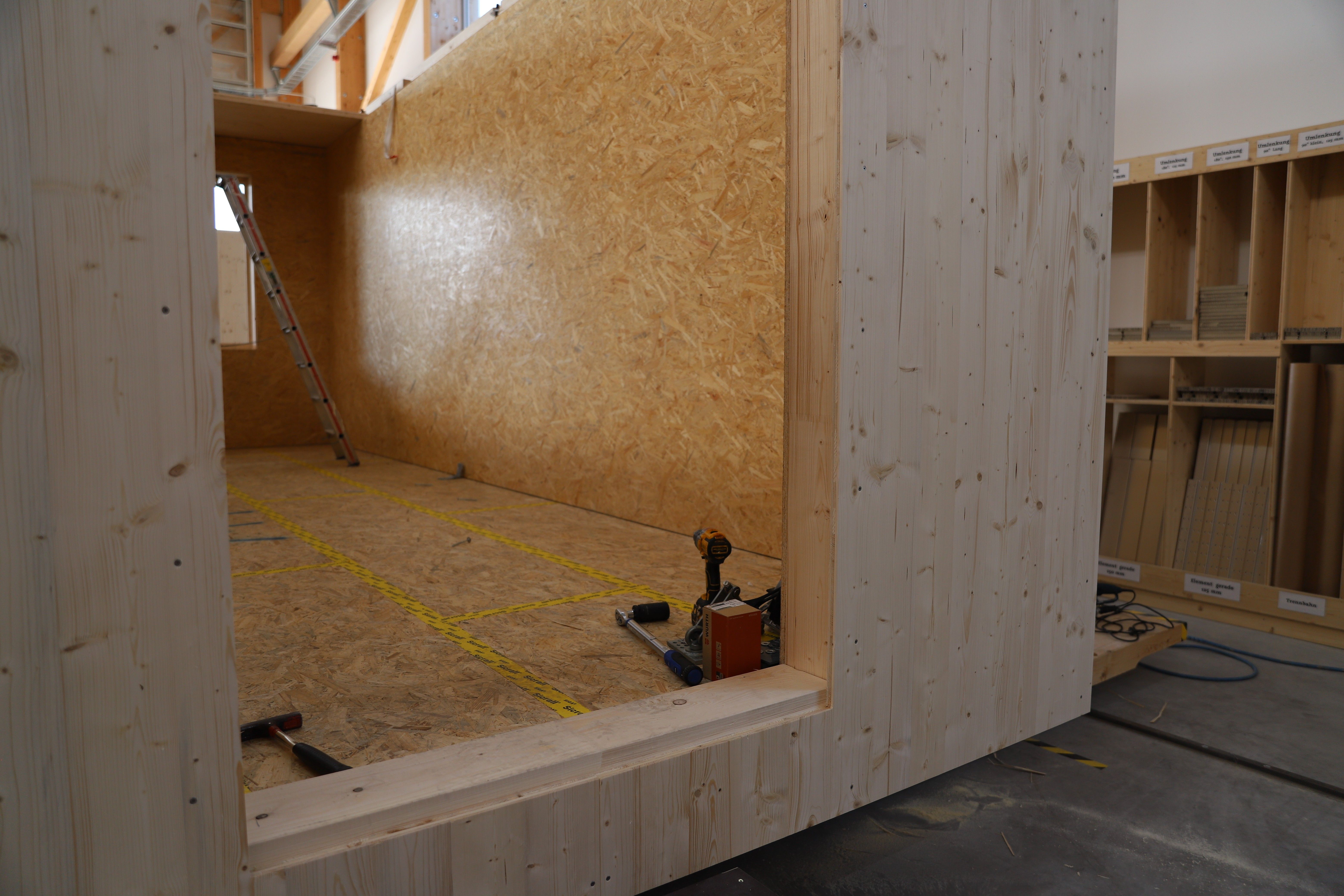 Blick in einen Wagen im Bau: Holzwände und Bodenplatte in der Werkhalle