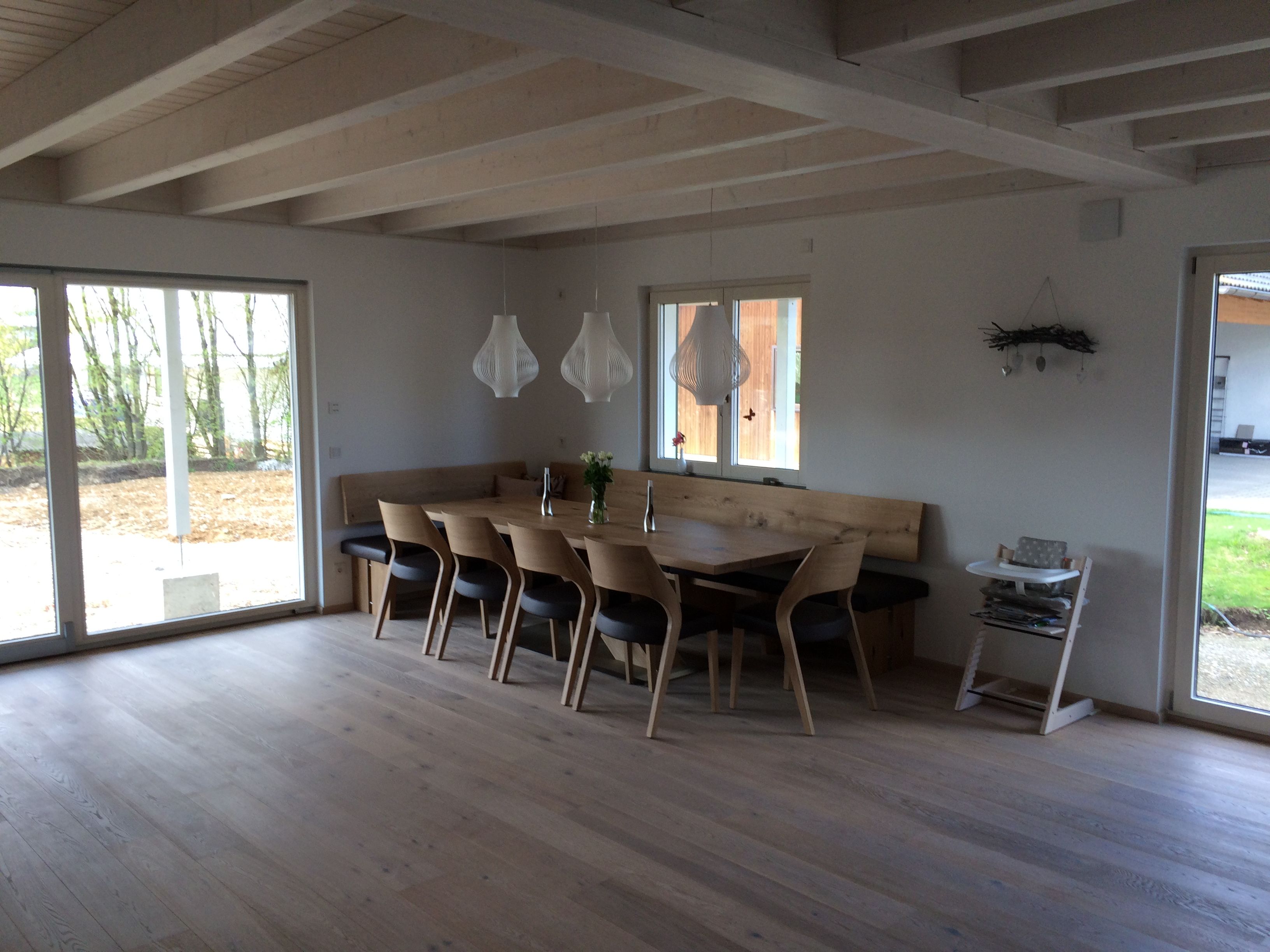 Großer Esstisch mit Holzstühlen und Eckbank unter Sichtbalkendecke