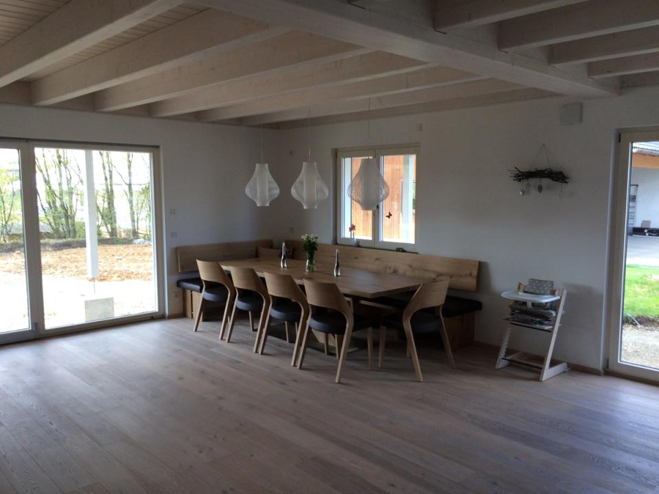 Großer Esstisch mit Holzstühlen und Eckbank unter Sichtbalkendecke