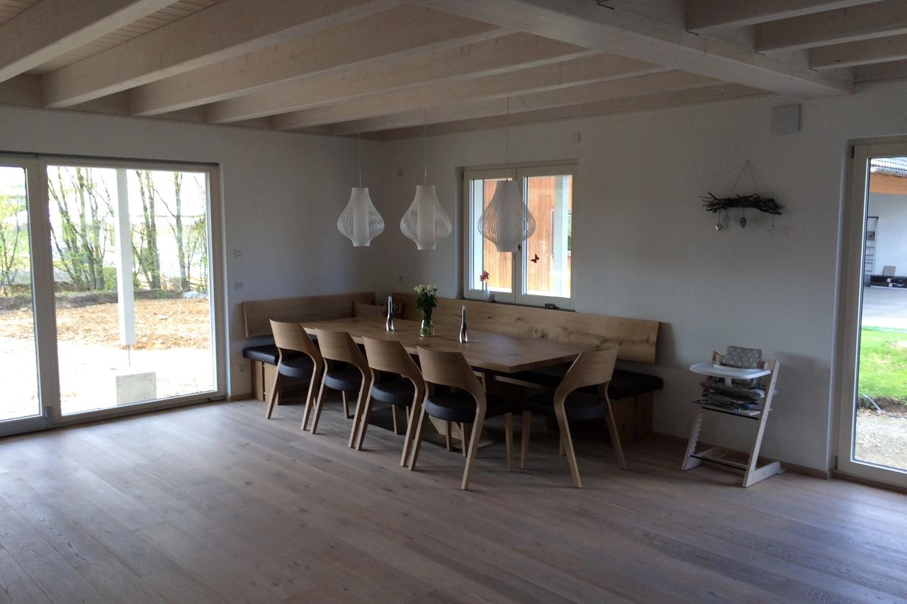 Großer Esstisch mit Holzstühlen und Eckbank unter Sichtbalkendecke