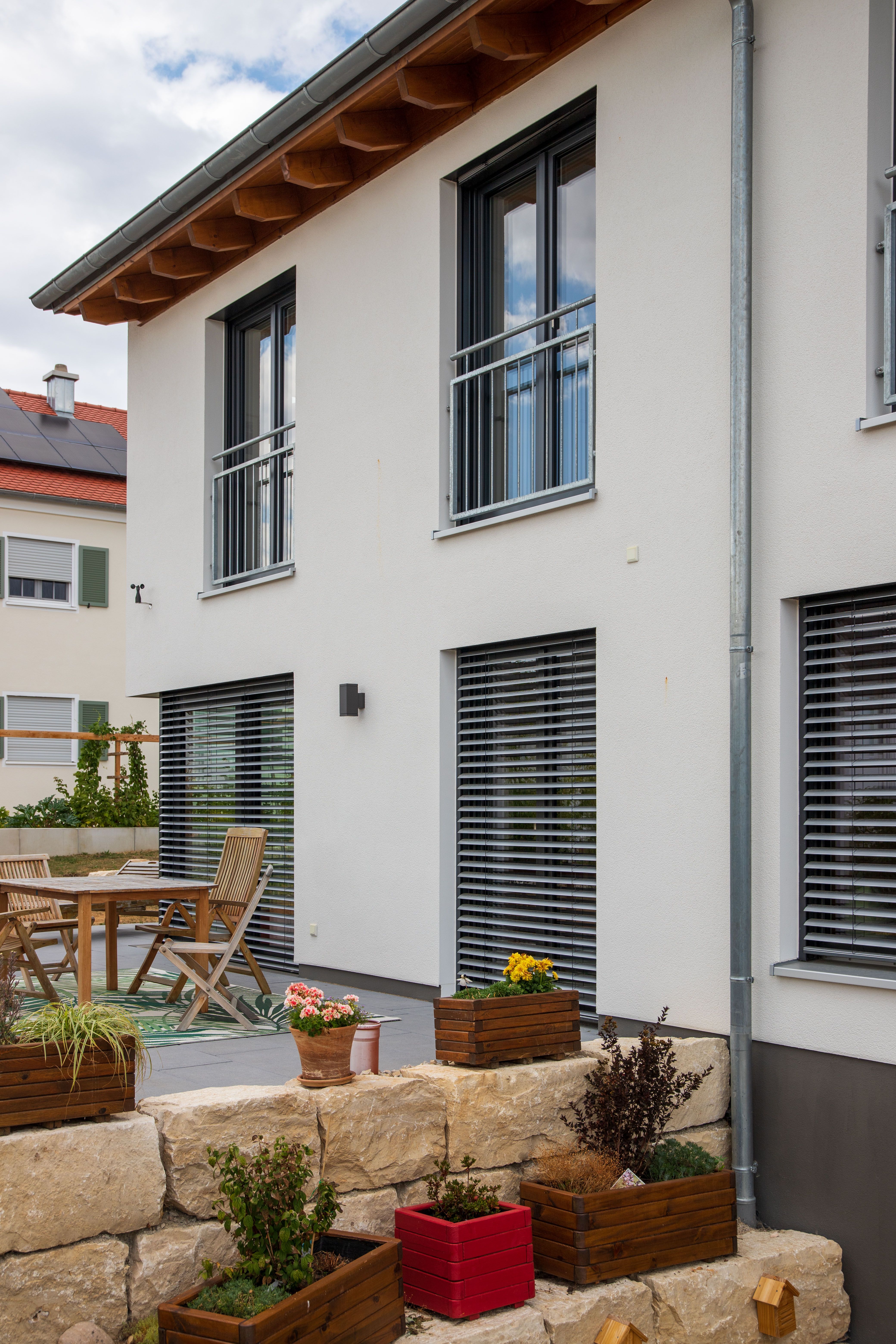 Terrasse mit Raffstores, Gartenmöbeln und Trockenmauer