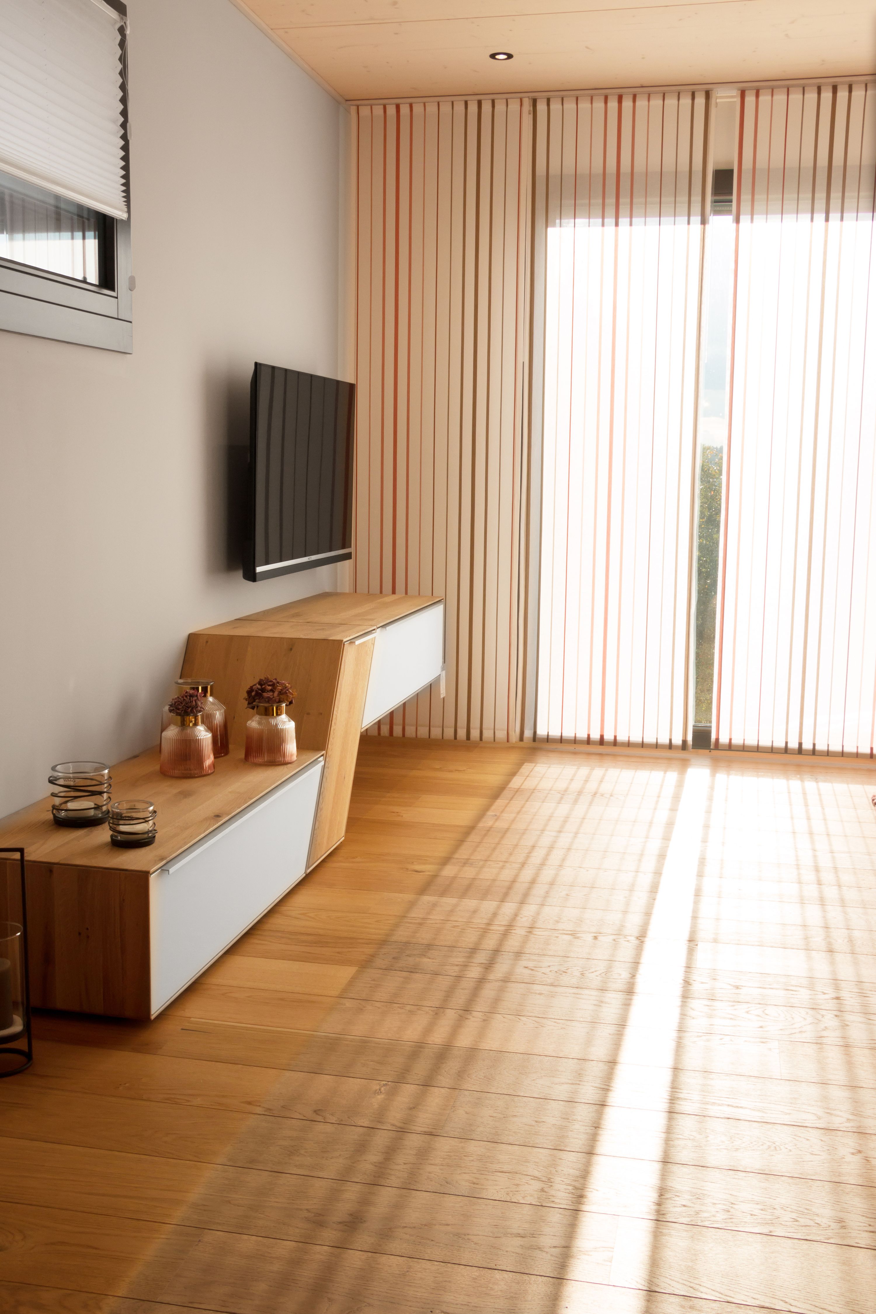 Wohnzimmer mit Eichen-Lowboard und Sonnenlicht durch Flächenvorhänge