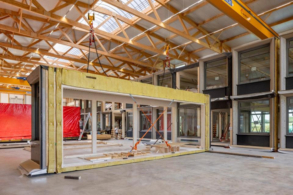 Gedämmtes Holzmodul hängt am Hallenkran in der Produktionshalle