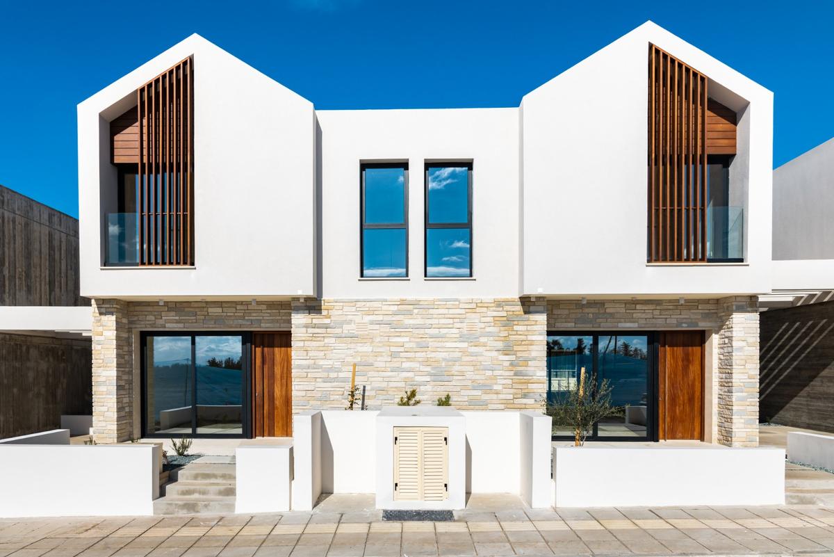 Λευκή σύγχρονη διπλοκατοικία με λιθινή πρόσοψη και ξύλινες λεπτομέρειες, ελκυστικό ακίνητο στην Κύπρο