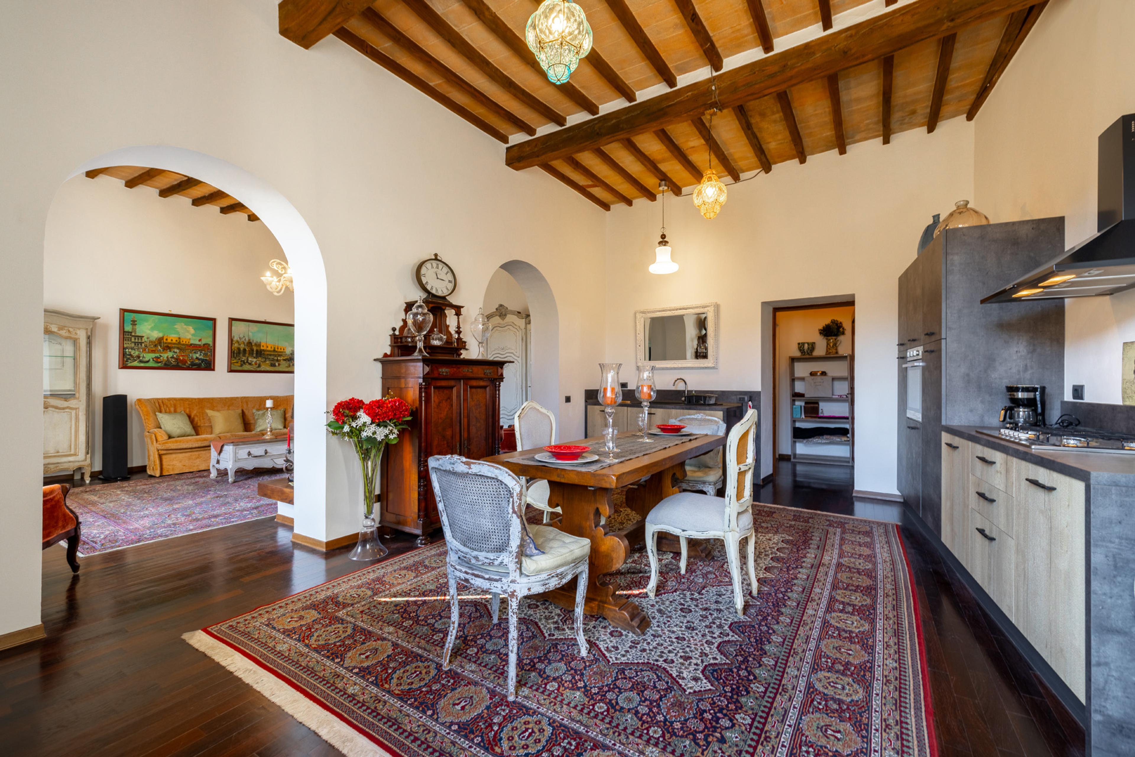 Stylish kitchen and dining area in Sansepolcro apartment – elegant interior with wooden beams, antique furniture, and rustic finish. Property for sale in Tuscany.
