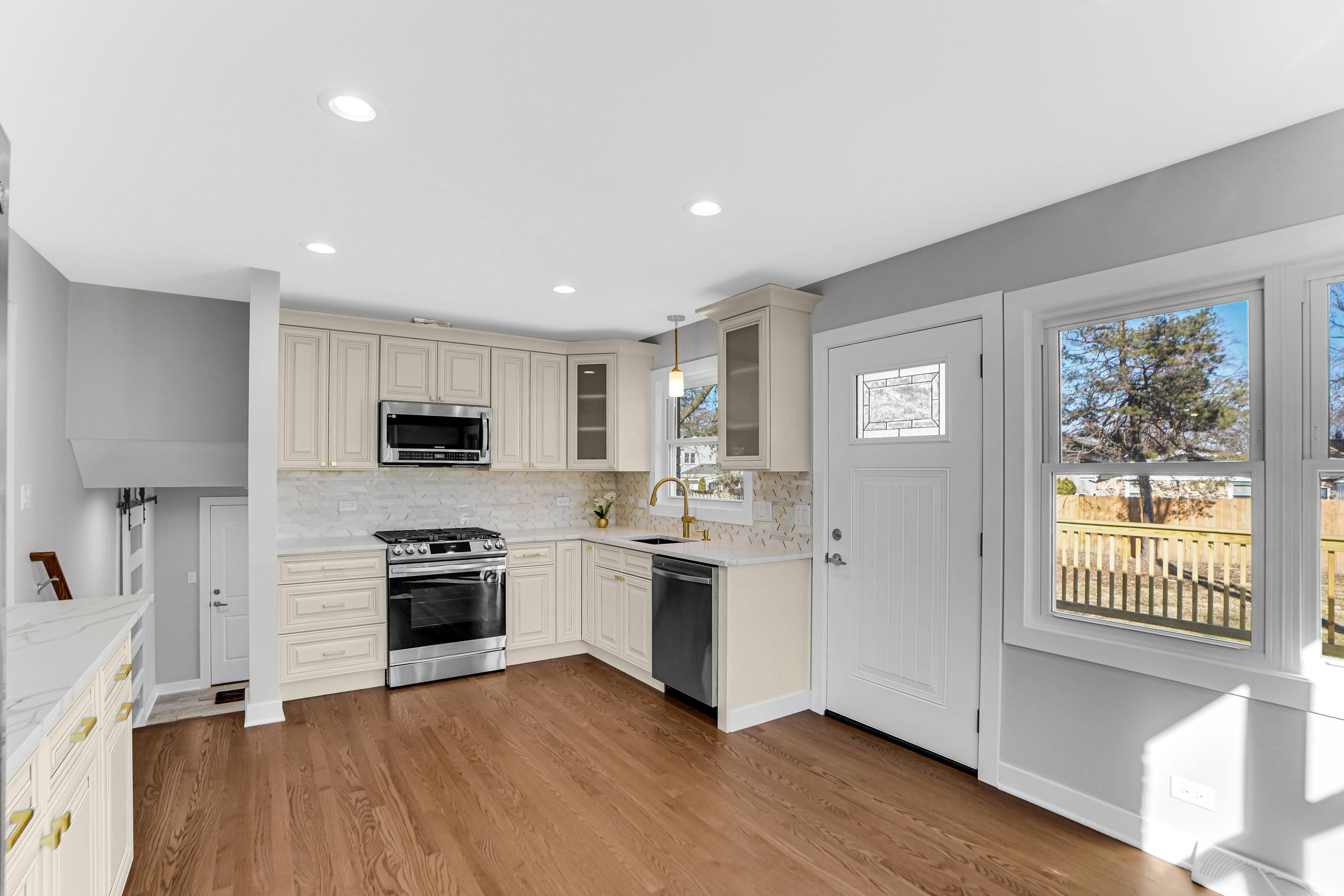 Cocina elegante en una casa en venta en Chicago: armarios claros clásicos, encimeras de mármol, modernos electrodomésticos y grandes ventanales con vistas al jardín. Interior espacioso y bien iluminado, ideal para familias. ¡Consulta las ofertas de casas en Chicago!