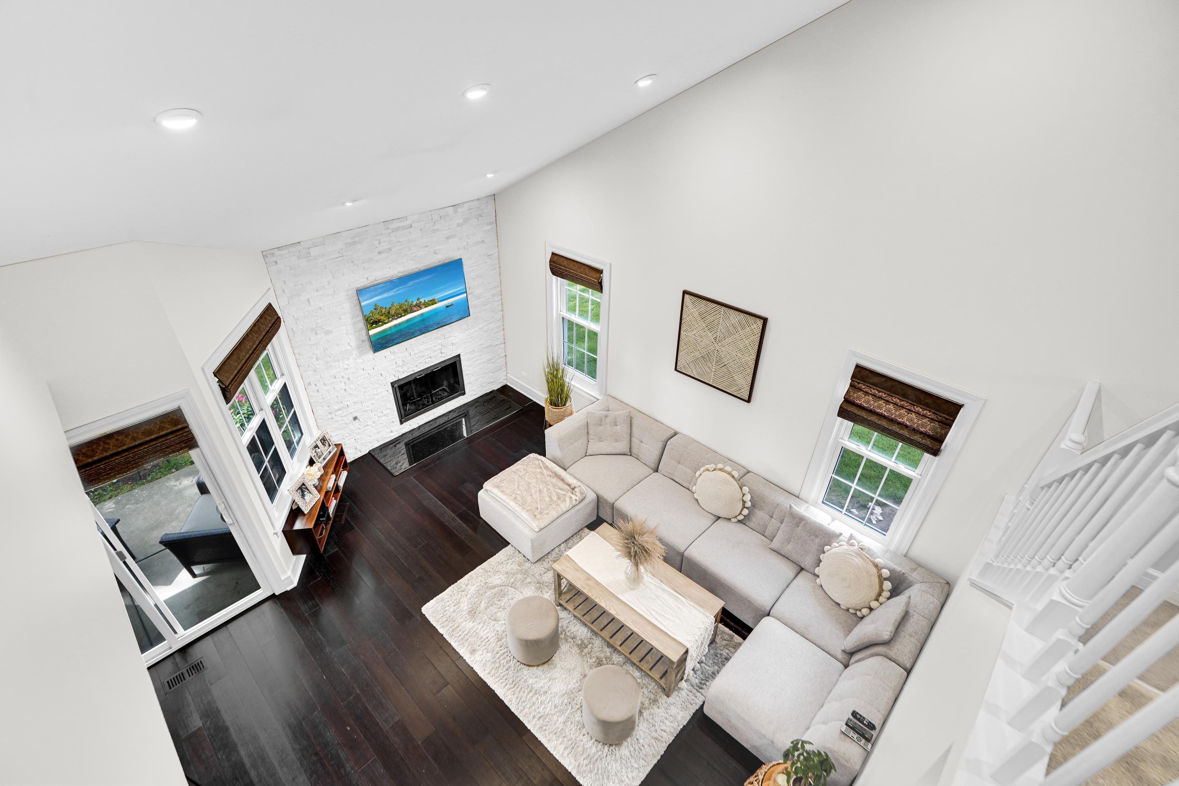 Amplia sala de estar en un apartamento en venta en Chicago: interior moderno con techo alto, grandes ventanales, chimenea y un elegante sofá esquinero. Ideal para relajarse y reuniones familiares. ¡Consulta las ofertas de propiedades en Chicago!