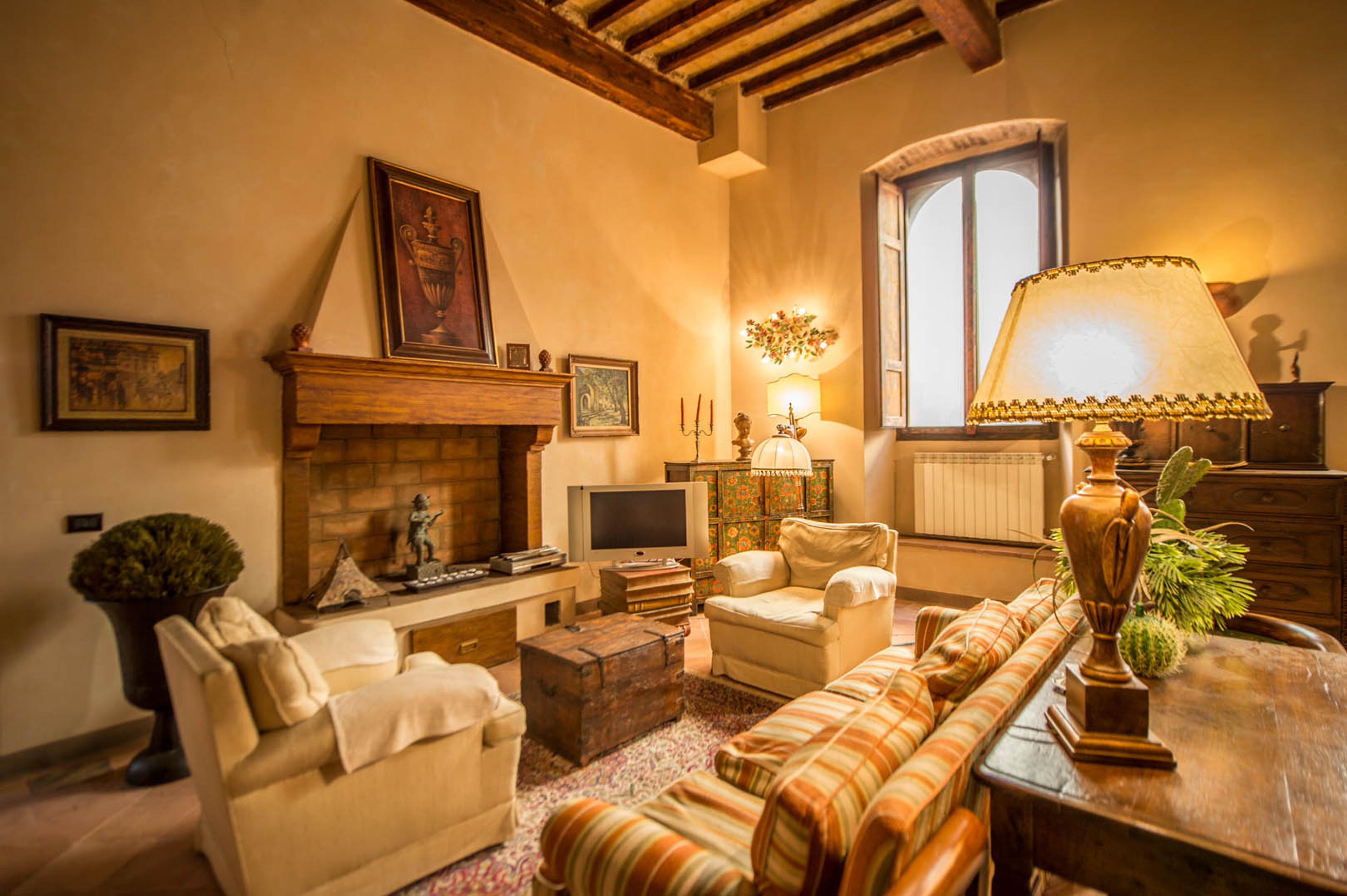 Stylish interior of an apartment in Sansepolcro – traditional Tuscan living room with a fireplace, wooden beams, and rustic decor. Ideal property in Italy for sale.