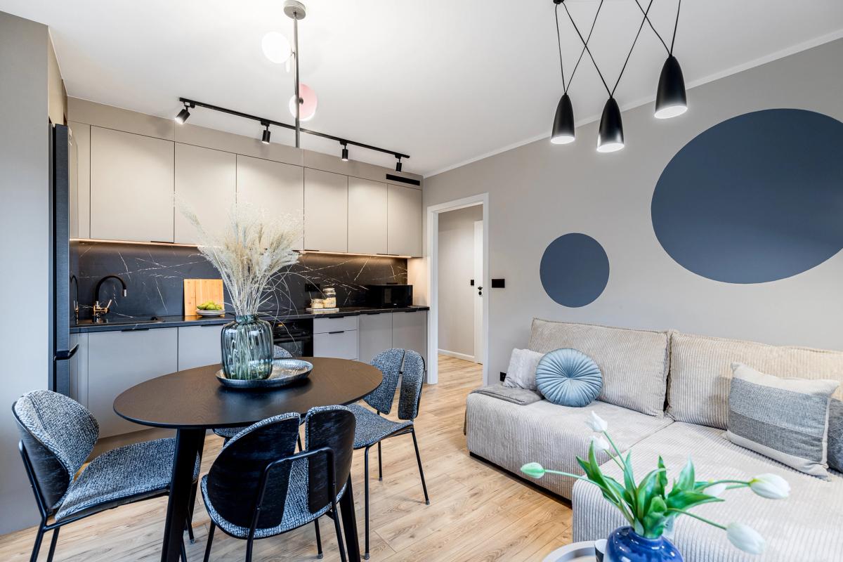 Moderní byt na prodej ve Wrocławi – stylový obývací pokoj s kuchyňským koutem, elegantním osvětlením a designovým nábytkem. Ideální investice do nemovitostí ve Wrocławi 2025.