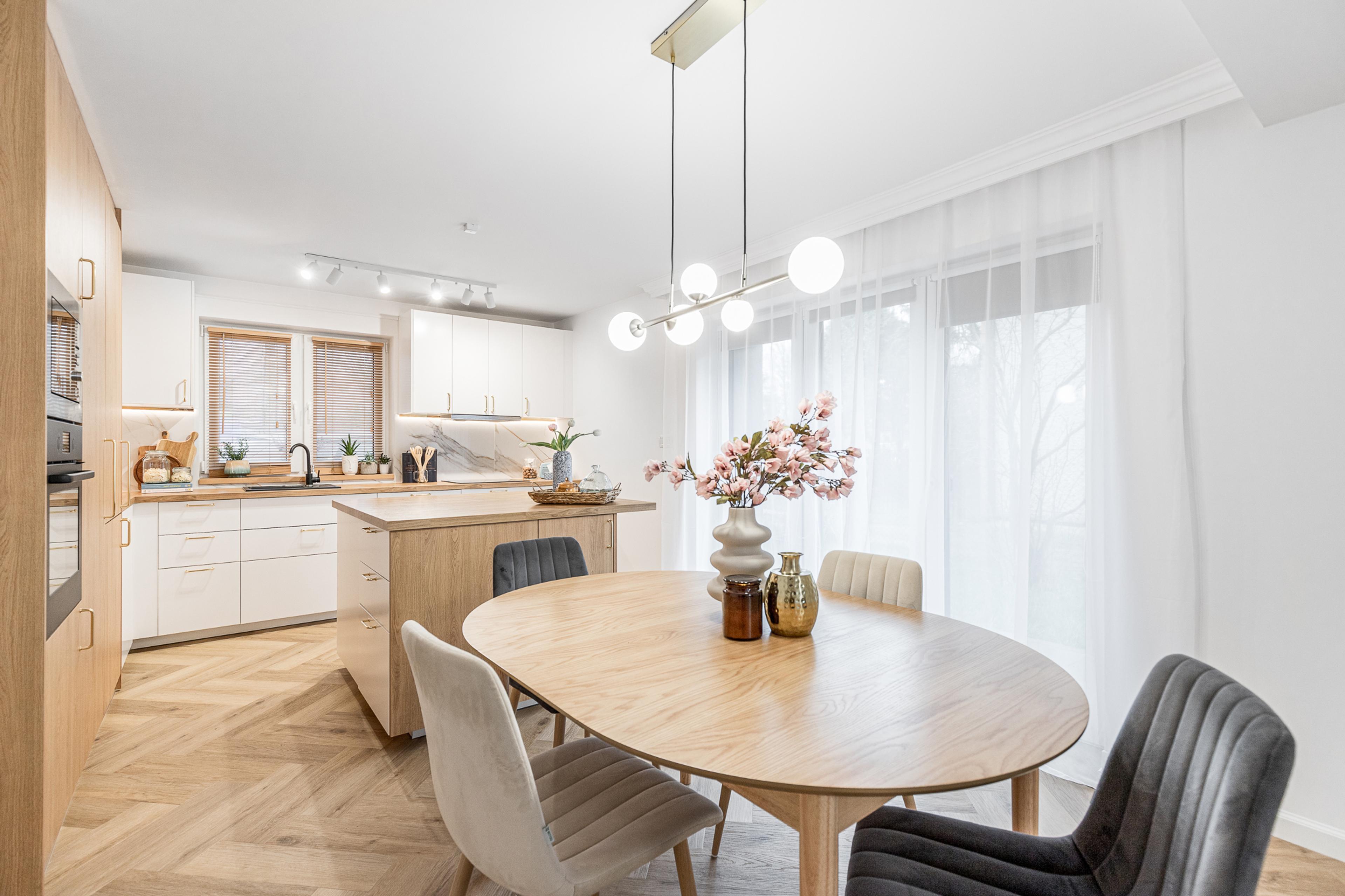 Cozinha elegante e sala de jantar em apartamento para aluguel em Wrocław – design sofisticado, acabamentos em madeira e grandes janelas. Imóvel ideal para investimento em aluguel de longo ou curto prazo.