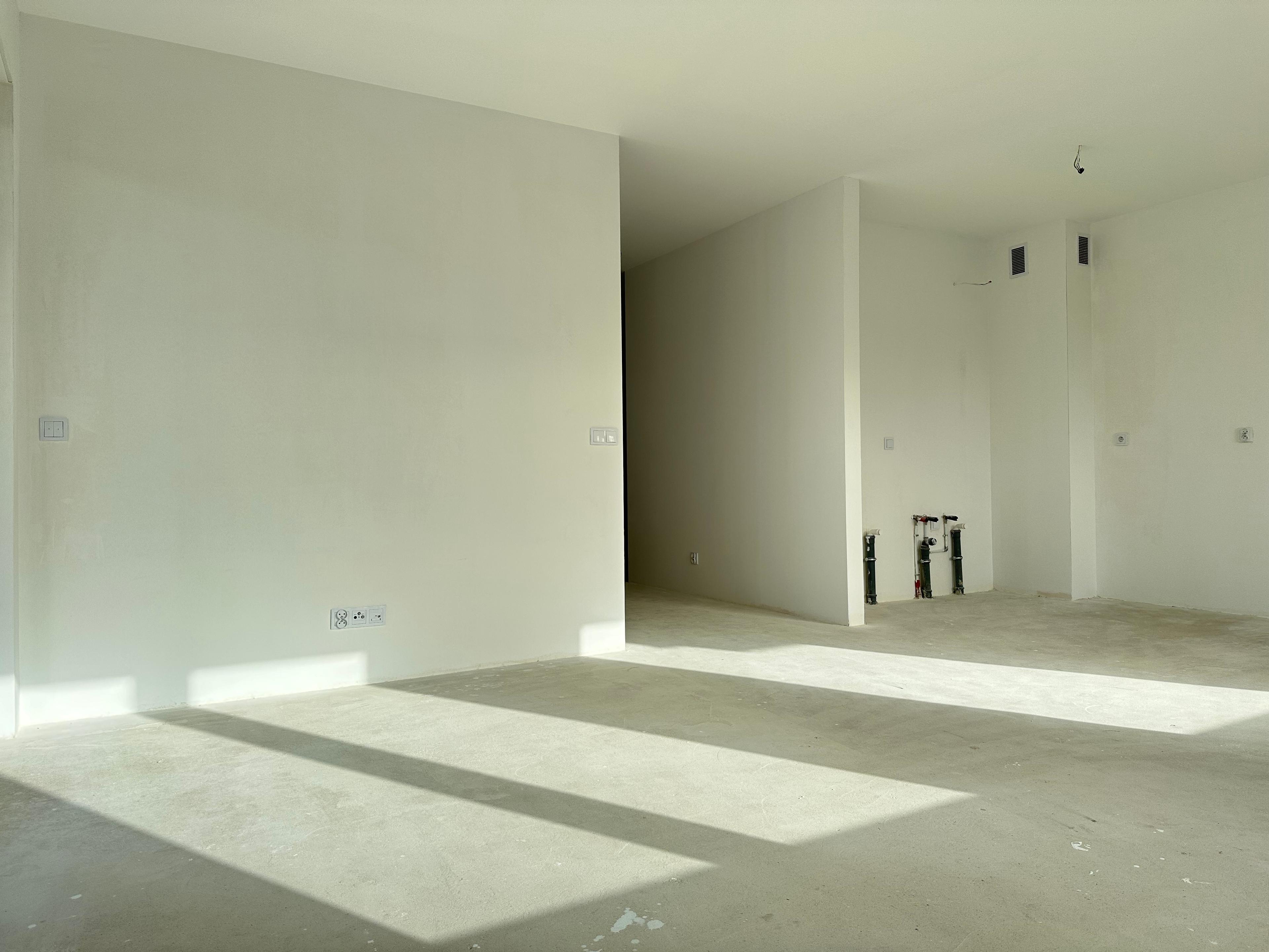 Appartement moderne en état de développement – intérieur spacieux avec beaucoup de lumière naturelle. Espace ouvert avec kitchenette et installations prêtes à être installées. Base idéale pour un aménagement personnel.