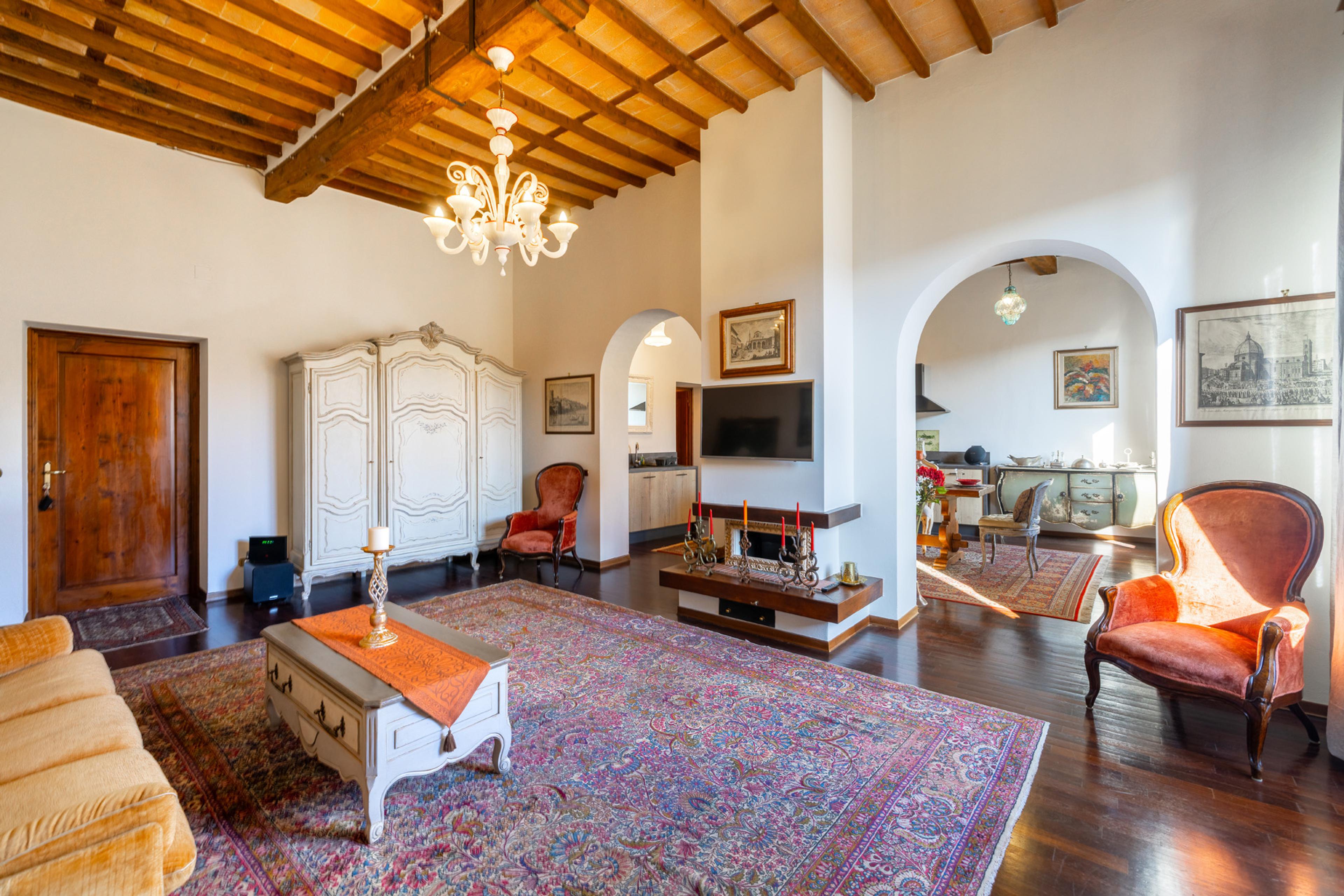 Elegant apartment for rent in Tuscany – spacious living room in classic style with wooden beams and rustic decor. Luxury property for sale in Sansepolcro.