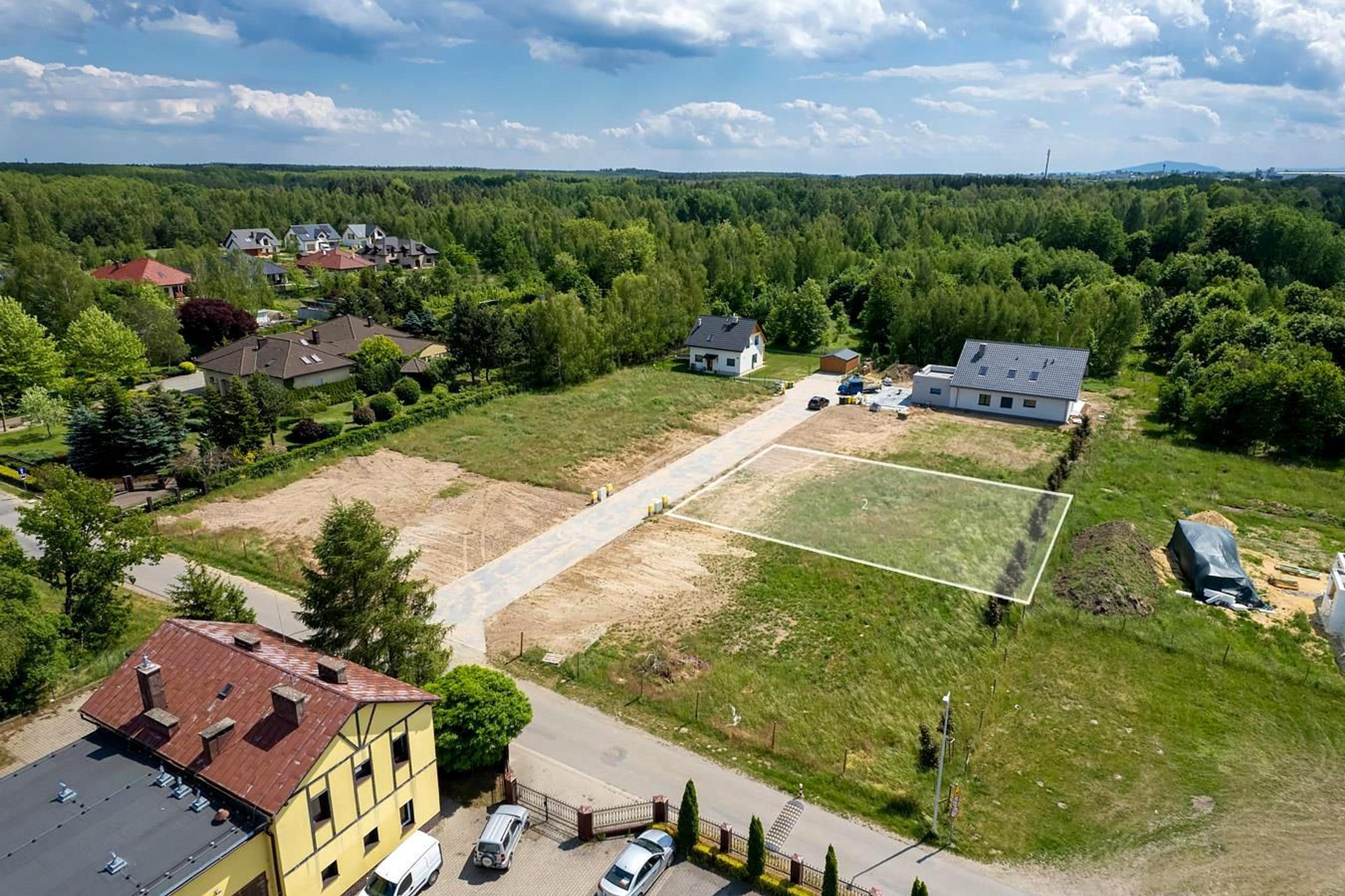 Terrain à bâtir à vendre dans un bel environnement – vue aérienne d'un espace vert avec de nouvelles constructions résidentielles. Environnement paisible, entouré de forêt et de maisons individuelles, idéal pour investir ou construire une maison.