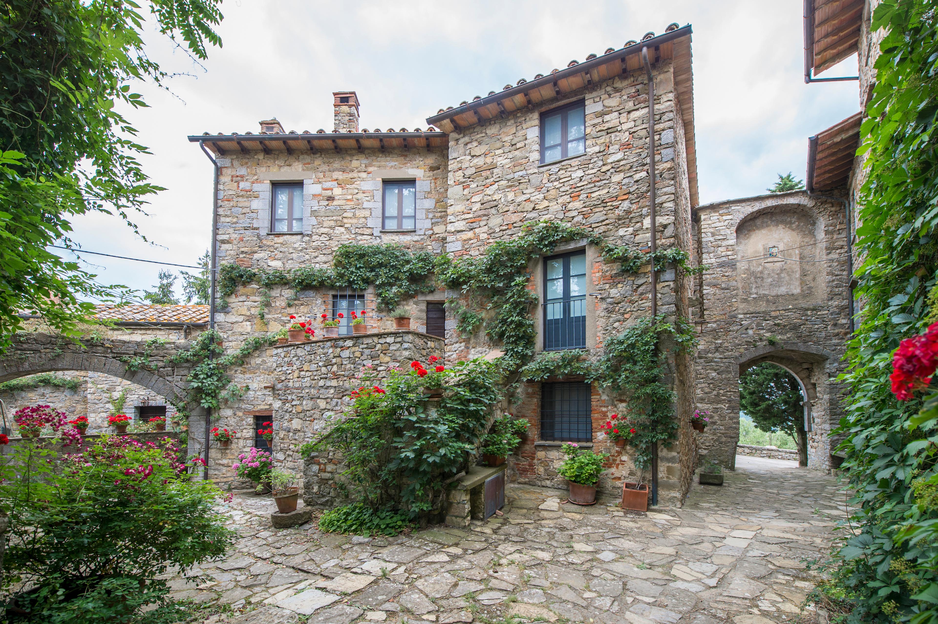 Storica casa in pietra in vendita in Umbria, ricoperta di vite, ideale per chi cerca una proprietà in Italia con atmosfera di cittadina medievale.