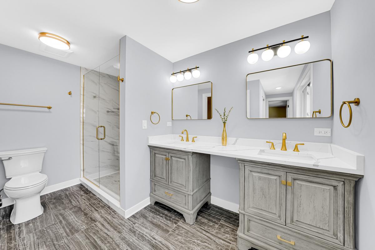 Baie luxoasă într-o casă de vânzare în Chicago – chiuvetă dublă cu blat din marmură, accente aurii elegante și duș modern cu geamuri. Interior spațios, premium, ideal pentru cumpărători exigenți. Vezi oferte imobiliare în Chicago!