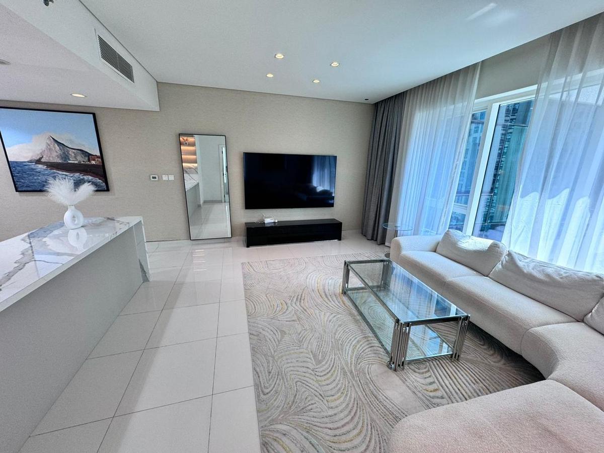 Vaalea, moderni olohuone Palm Jumeirah -asunnossa, valkoinen sohva, lasinen sohvapöytä ja suuri televisio