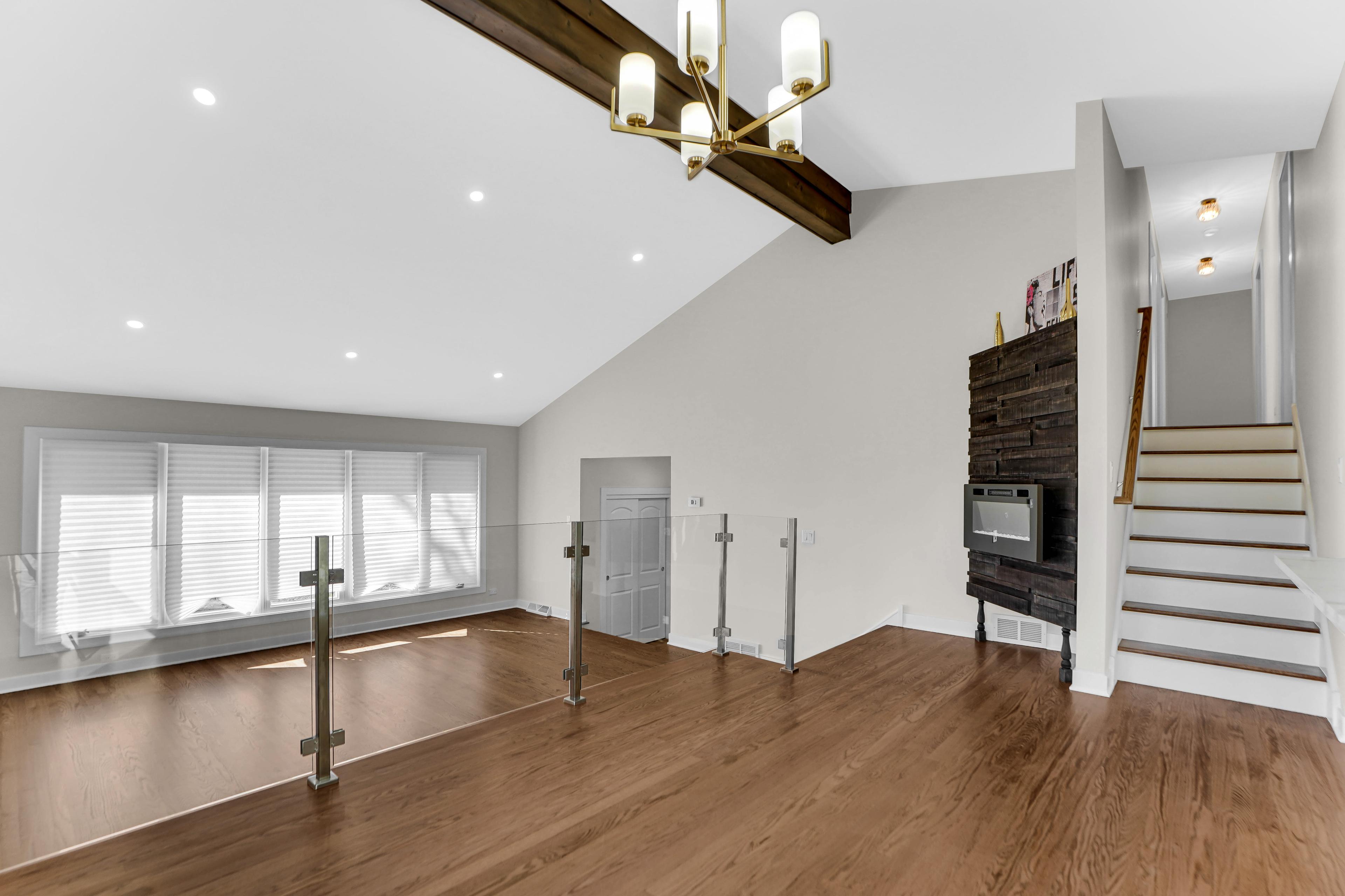 Amplia sala de estar en una casa nueva en venta en Chicago: techos altos, iluminación moderna, suelos de madera y barandilla de cristal. Espacio elegante ideal para decorar a tu gusto. ¡Consulta las ofertas de propiedades en Chicago!